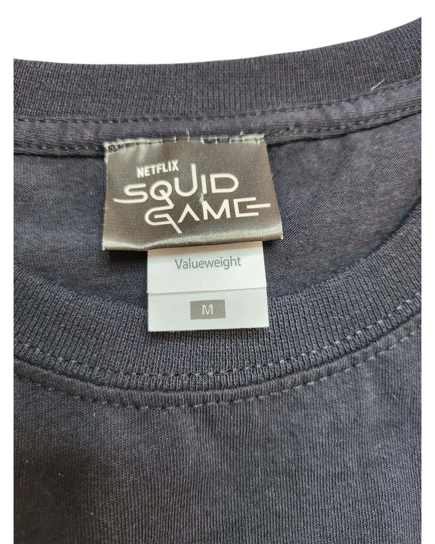 A dark gray Netflix Squid Game T-shirt in size M, labeled as an upcycled Breastfeeding & Pumping tee from touched out mama, merges popular culture with sustainability for a unique wardrobe addition.