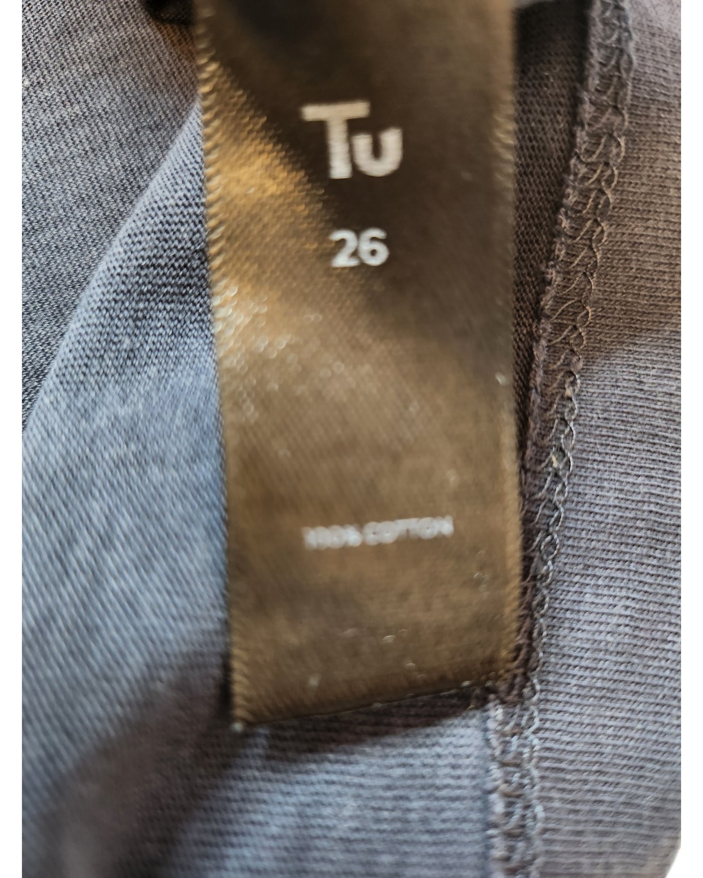 Close-up of a tag showing touched out mama and size UK26, attached to a gray, eco-friendly nursing & pumping t-shirt. Made from 100% cotton, featuring visible stitching that highlights sustainable style.