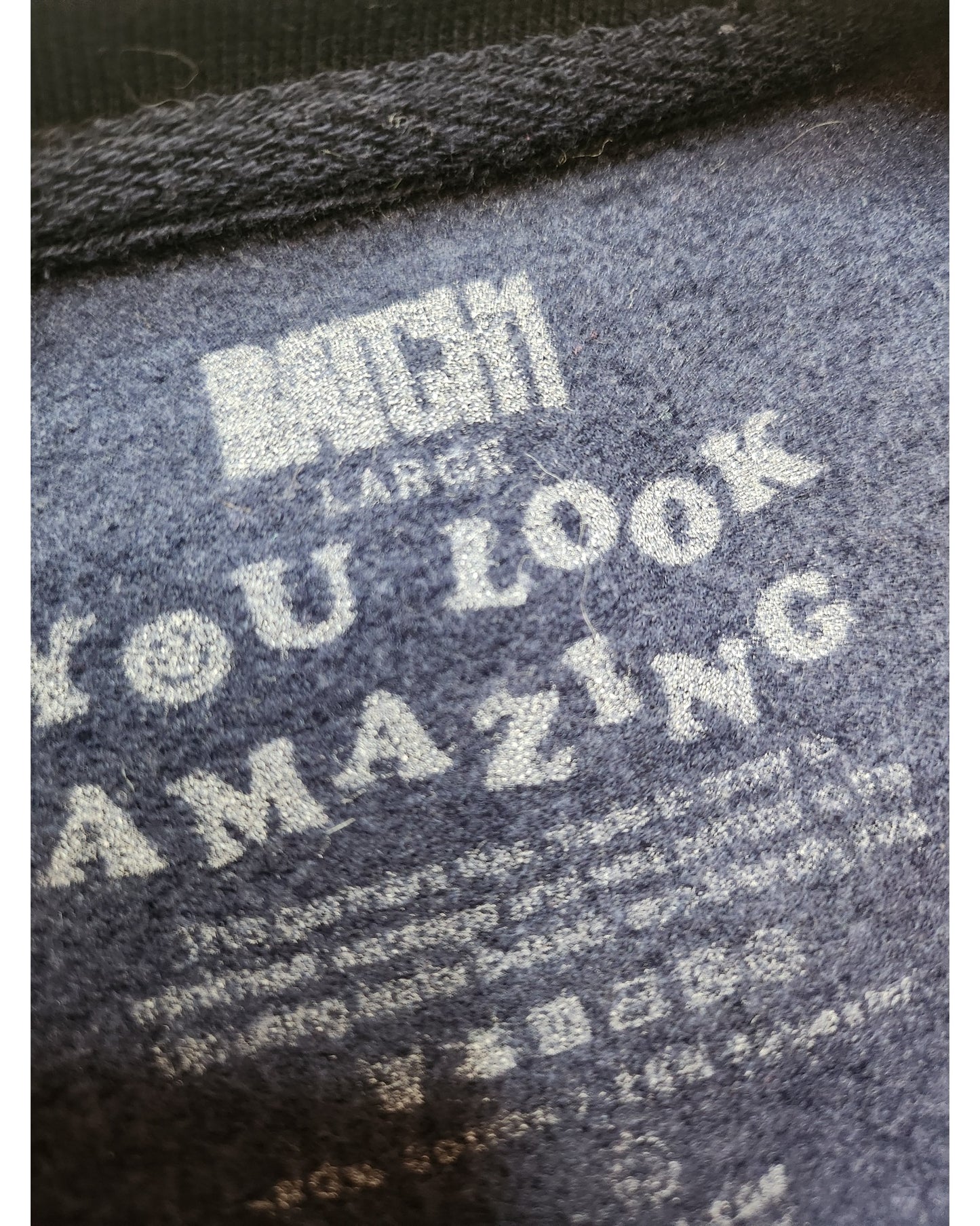 Close-up of preloved dark fabric with white text. Main text reads YOU LOOK AMAZING, with care and size info below, highlighting the beauty of the Upcycled Breastfeeding & Pumping Rainbow Sweatshirt L by touched out mama.