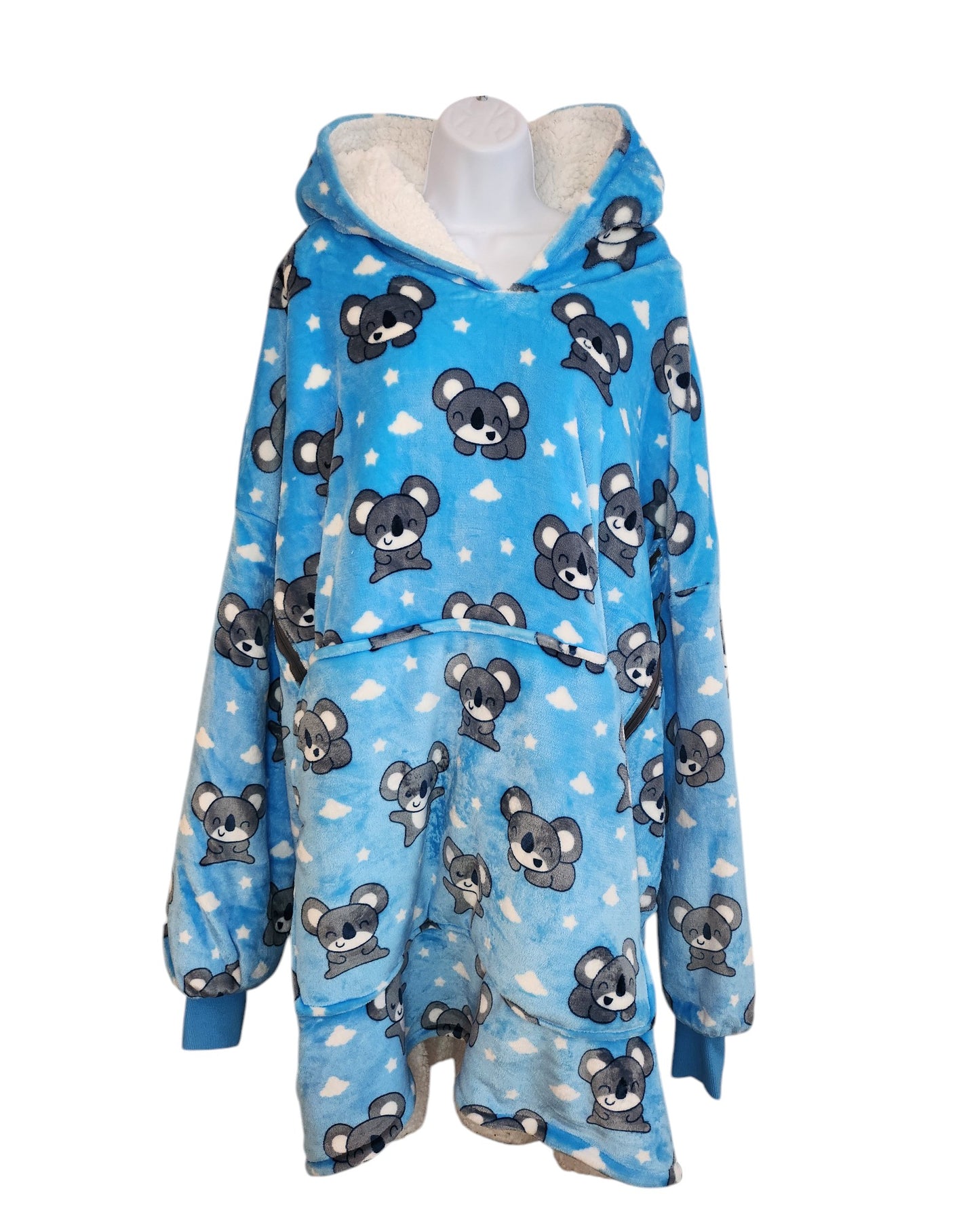 This upcycled breastfeeding and pumping koala Oodie by touched out mama is a blue hooded blanket with gray animal faces and white clouds. Made from plush fabric, it features long sleeves and an oversized fit, beautifully showcased on a mannequin.