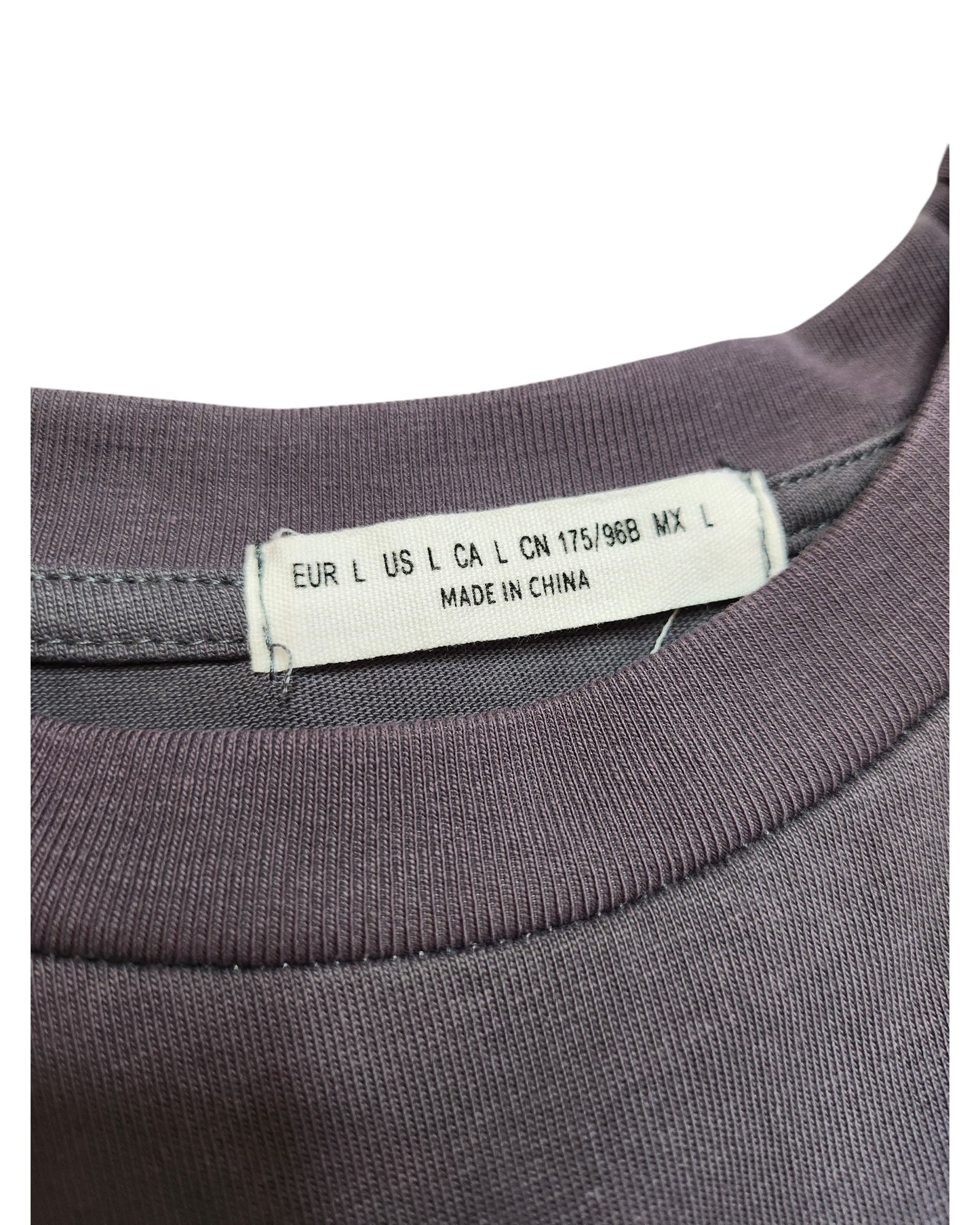 A close-up of the clothing tag on this preloved purple garment from touched out mama reveals size labels: EUR L, US L, CA L, CN 175/96B, MX L. It also reads Made in China, sewn neatly into the neckline of the Upcycled Breastfeeding & Pumping White Fox t-shirt.