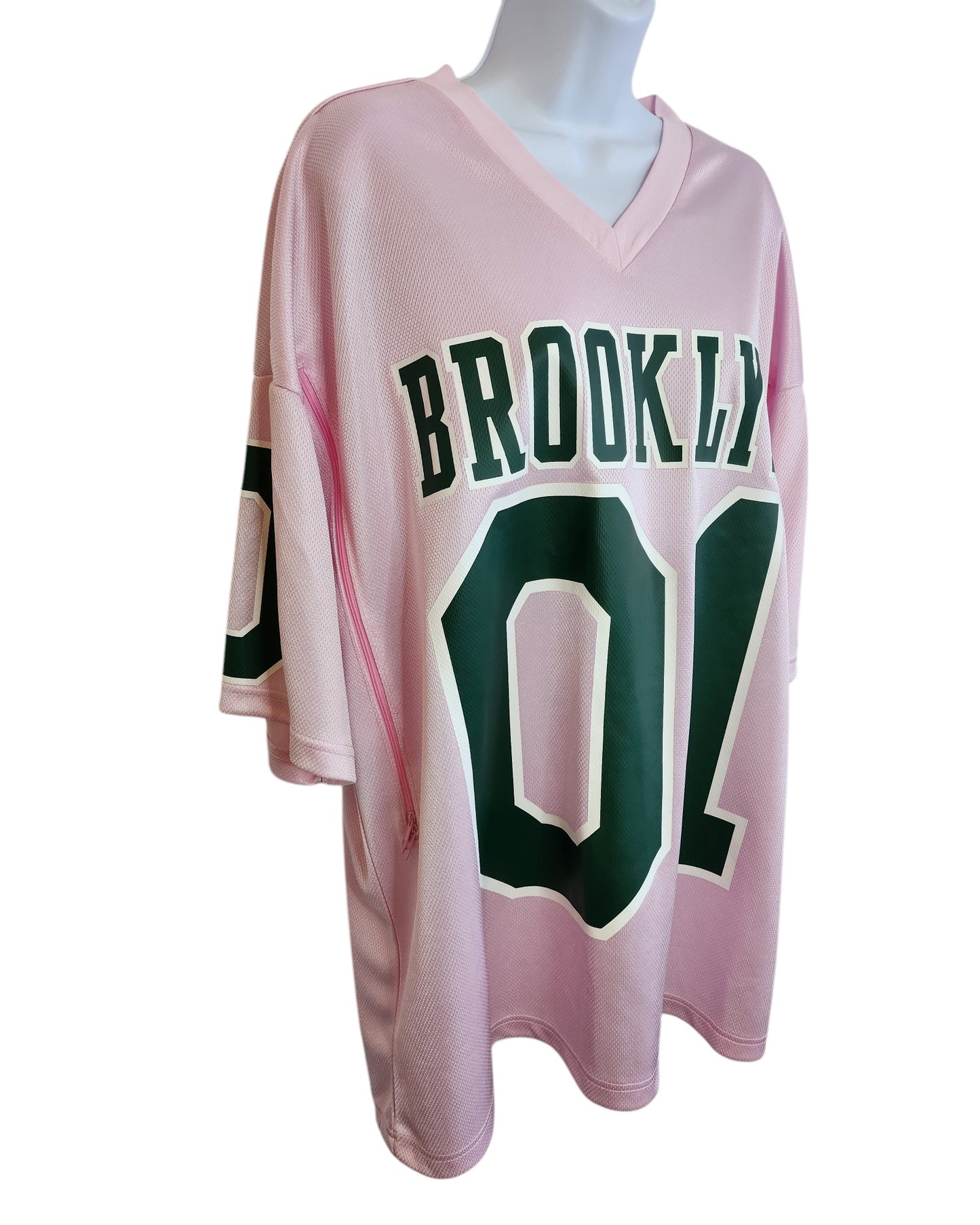 The H&M Upcycled Breastfeeding & Pumping Football Jersey XL is a light pink, eco-friendly oversized top featuring BROOKLYN 01 in bold green on the front, shown on a mannequin torso.