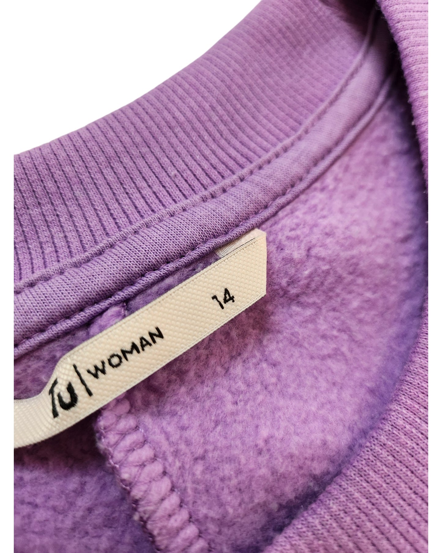 Close-up of a purple Upcycled Breastfeeding & Pumping Sweatshirt Dress by Tu in UK14, showing a white “WOMAN” label. The soft, fleecy interior reflects eco-friendly materials and the brand’s thoughtful design.