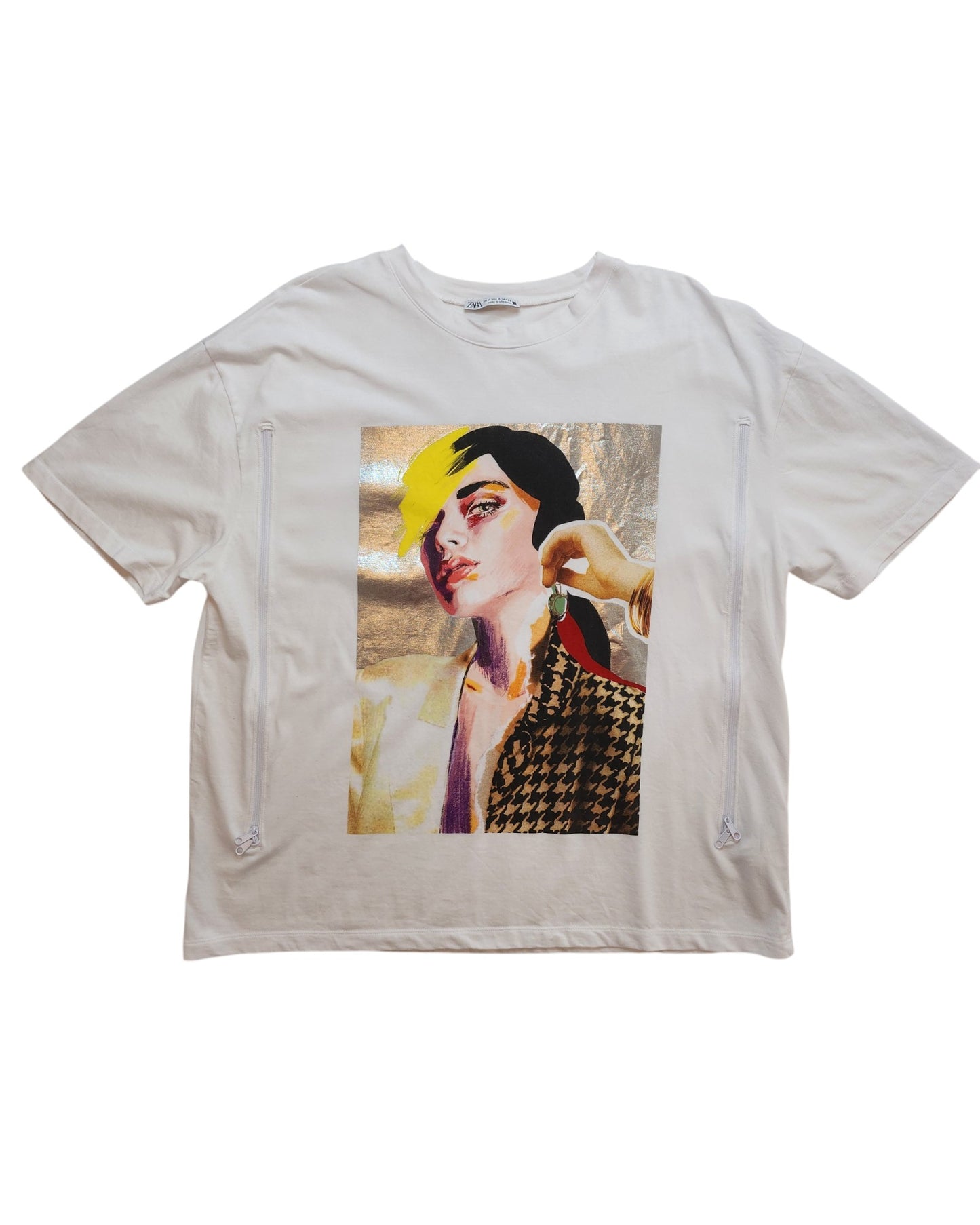 The Upcycled Breastfeeding & Pumping Silver Face T-shirt M by touched out mama features a colorful abstract portrait with vibrant yellow, red, and black hair hues. The design includes houndstooth shoulders on a metallic silver background and is crafted from upcycled clothing.