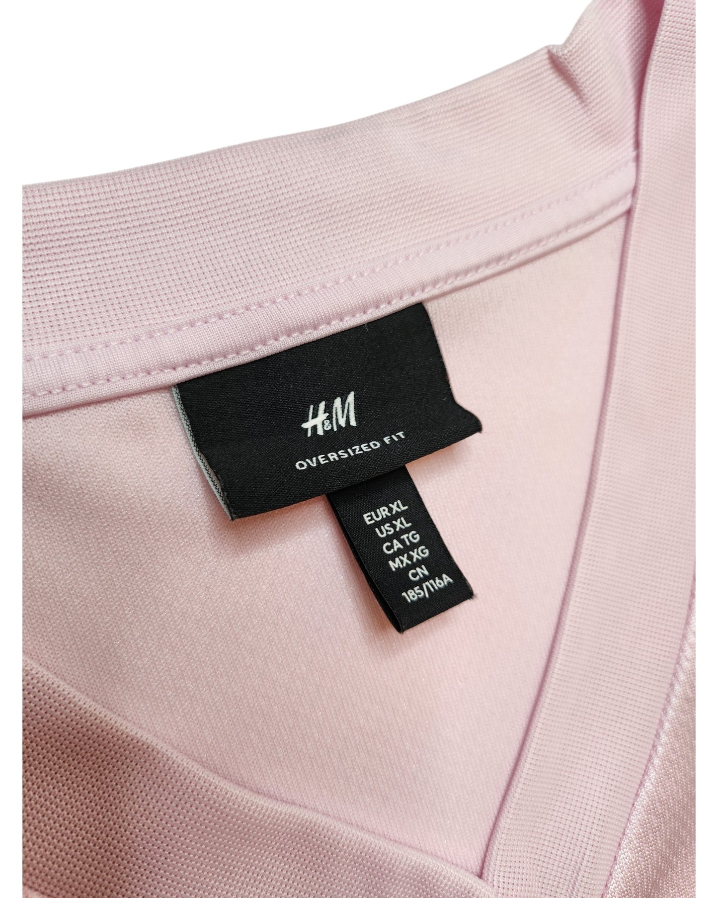 Close-up of an H&M Upcycled Breastfeeding (Nursing) & Pumping Football Jersey XL in light pink, showing the collar and labels. Oversized fit makes it ideal for nursing, pumping, or anyone wanting comfy, eco-friendly clothing.