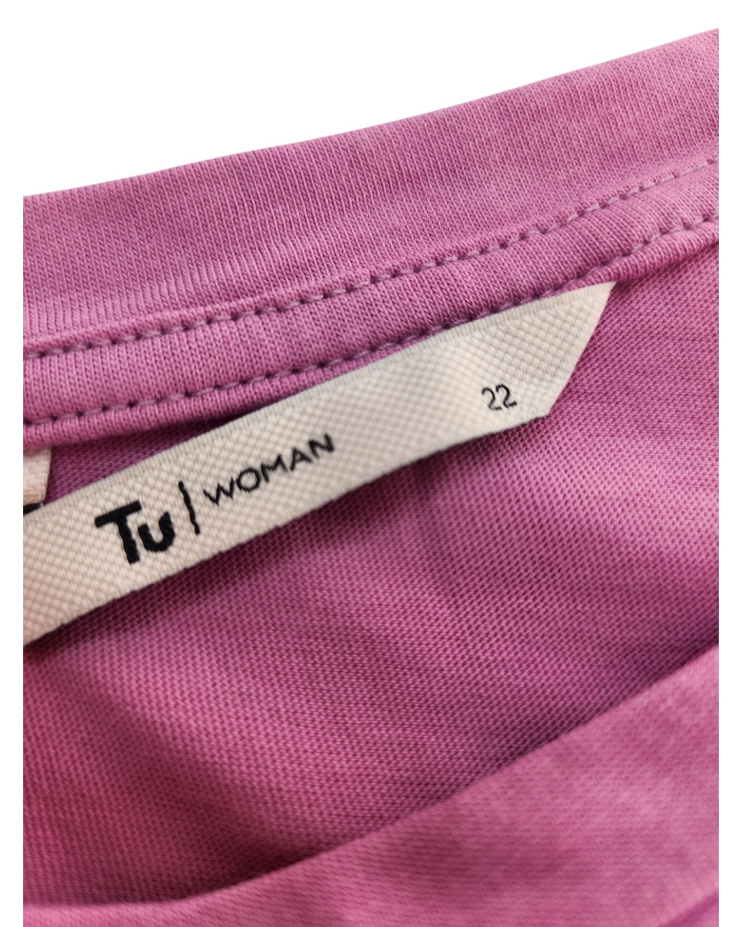 Close-up of a pink t-shirt labeled touched out mama and Woman, size UK22. From the eco-friendly line, it promotes sustainability through upcycled clothing.