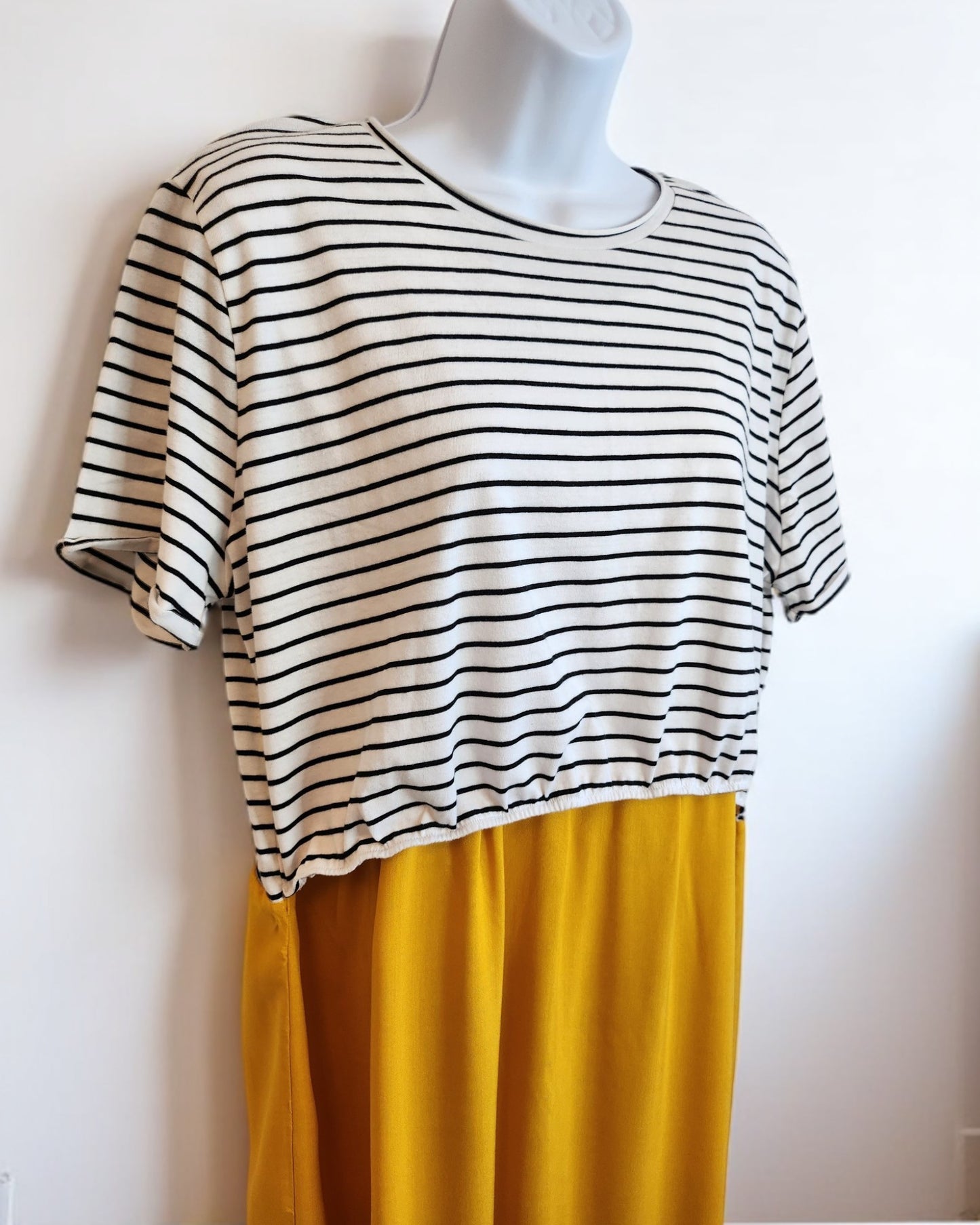 The Upcycled Breastfeeding & Pumping Stripe Ochre Maxi Dress by touched out mama, size M/L, features a black-and-white striped top with short sleeves and a flowing mustard yellow skirt. Set against a plain white background, this dress combines eco-friendly design with functional nursing wear.