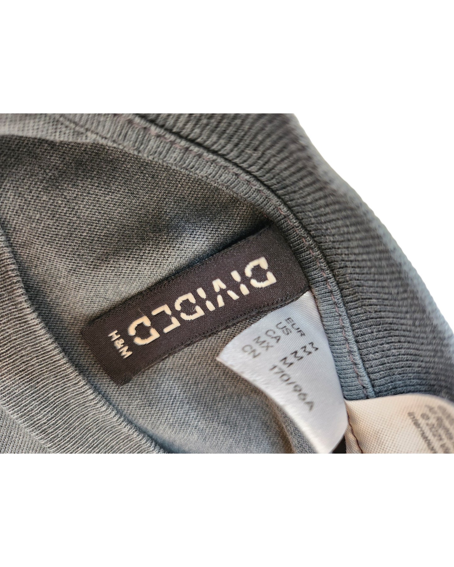 Close-up of the inside labels on a gray Upcycled Breastfeeding & Pumping Garfield t-shirt Dress M by touched out mama, showing a black DIVIDED tag and a white care label with size and washing instructions.