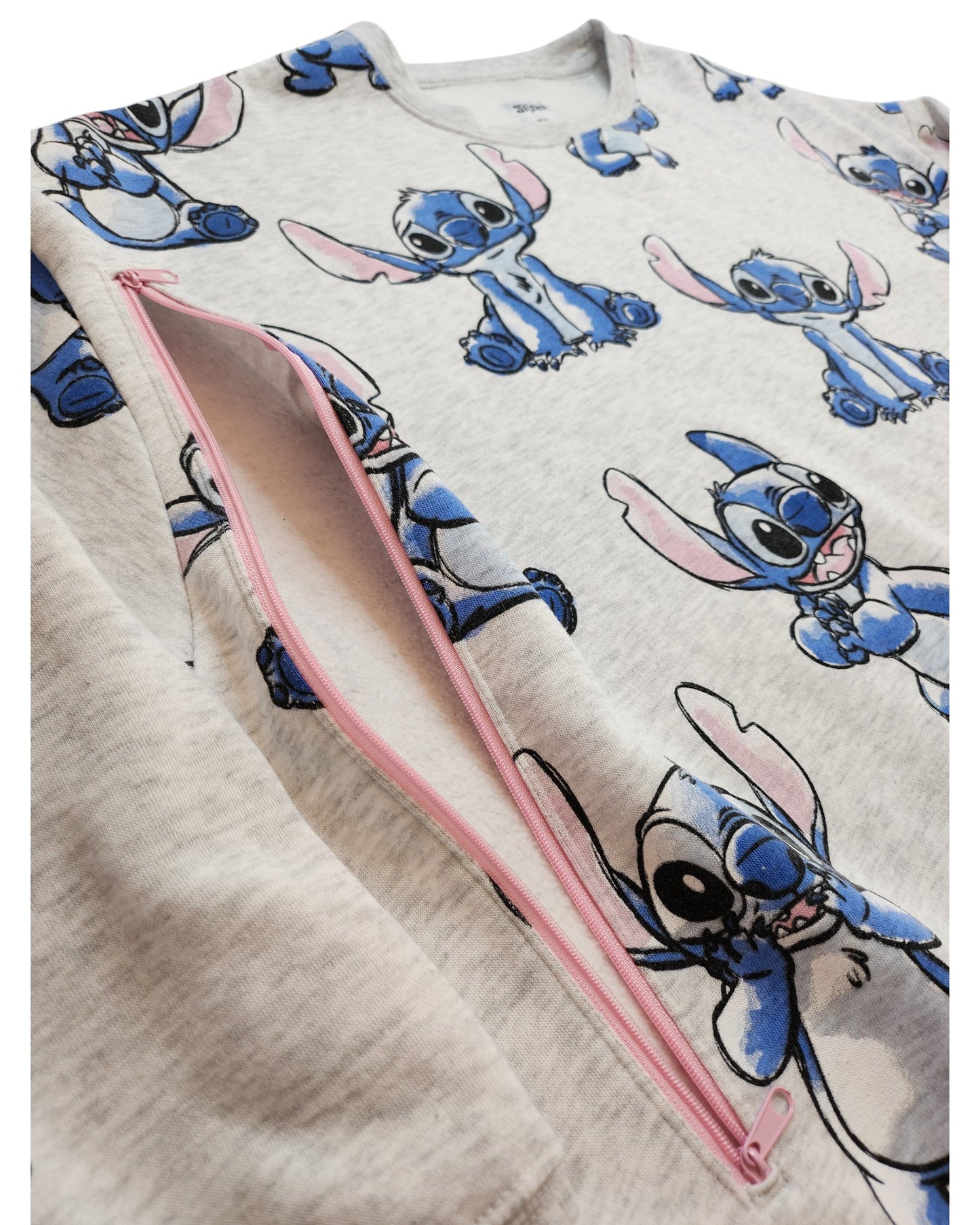 A close-up of the Primark Upcycled Breastfeeding & Pumping Stitch Disney Sweatshirt (2XL) in light grey, featuring playful blue Stitch cartoon prints and a pink diagonal zipper.