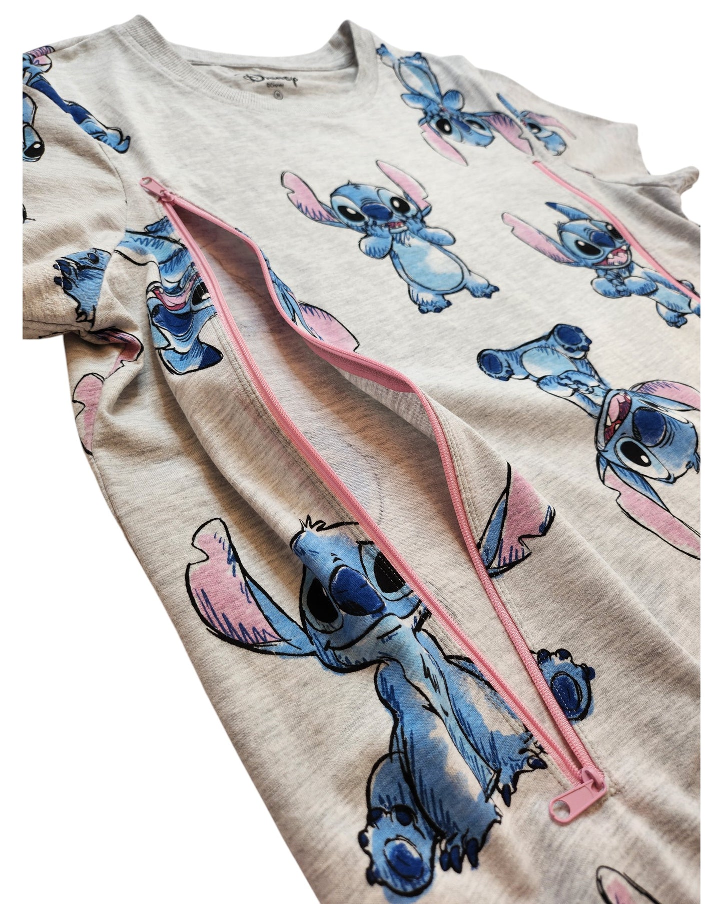 A close-up of the upcycled Stitch Disney t-shirt from touched out mama shows cartoon-style blue alien characters with pink ears. This gray breastfeeding and pumping shirt in medium features a partially open vertical pink zipper, blending style and sustainability.