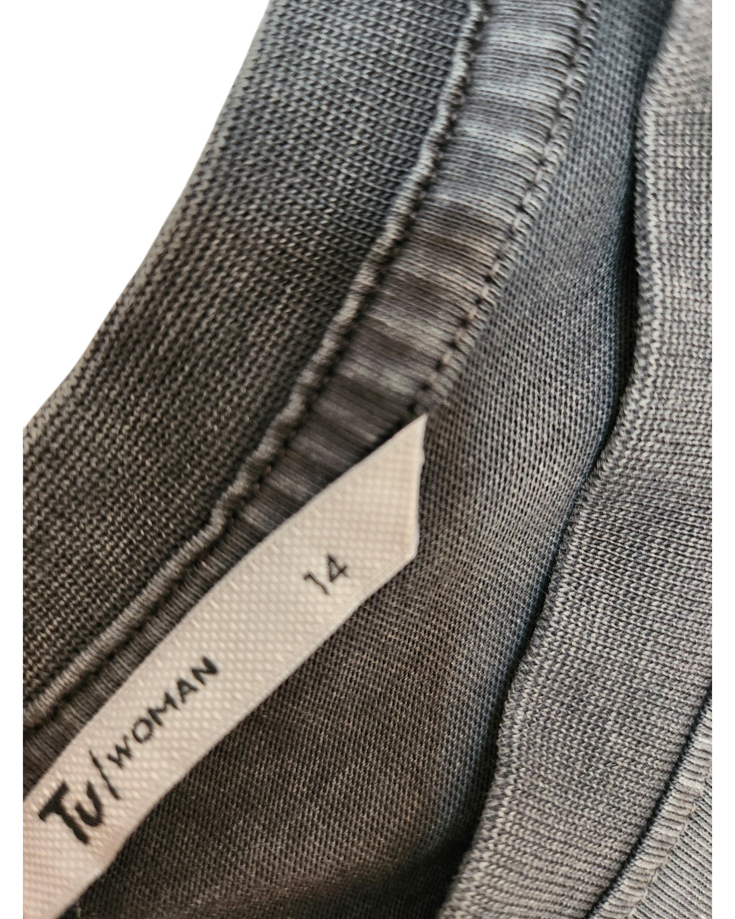 Close-up of a gray fabric collar with a touched out mama label. The label reads UK14. Crafted as part of sustainable fashion, the stitching and texture of the upcycled fabric are visible on the Upcycled Breastfeeding & Pumping Charcoal Floral Zip t-shirt.