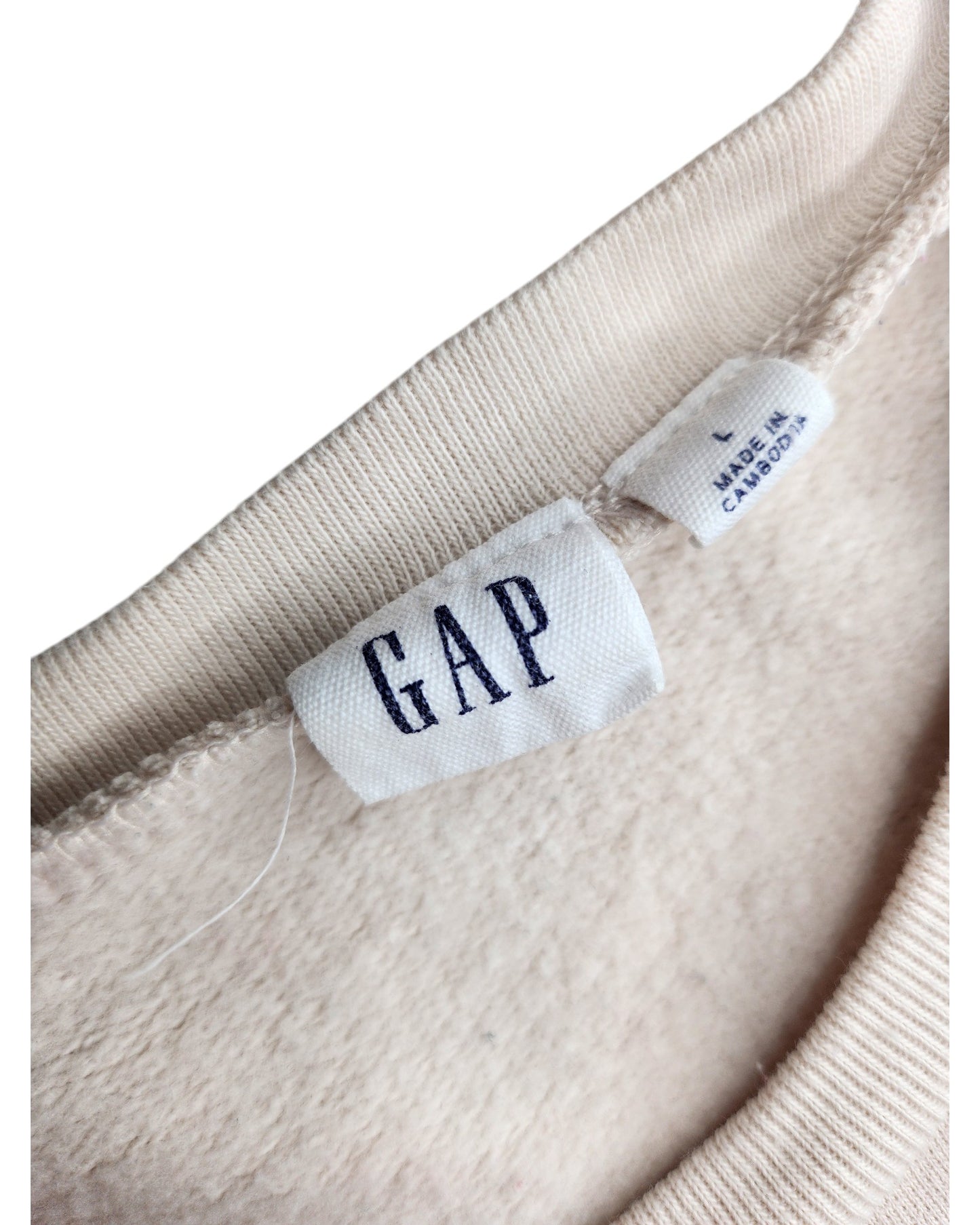 Close-up of the neck tag on a beige sweatshirt by touched out mama, with GAP in navy letters. Beneath it, a label reads L MADE IN CAMBODIA. This preloved, upcycled breastfeeding and pumping GAP sweatshirt has a soft, fleece-like texture.