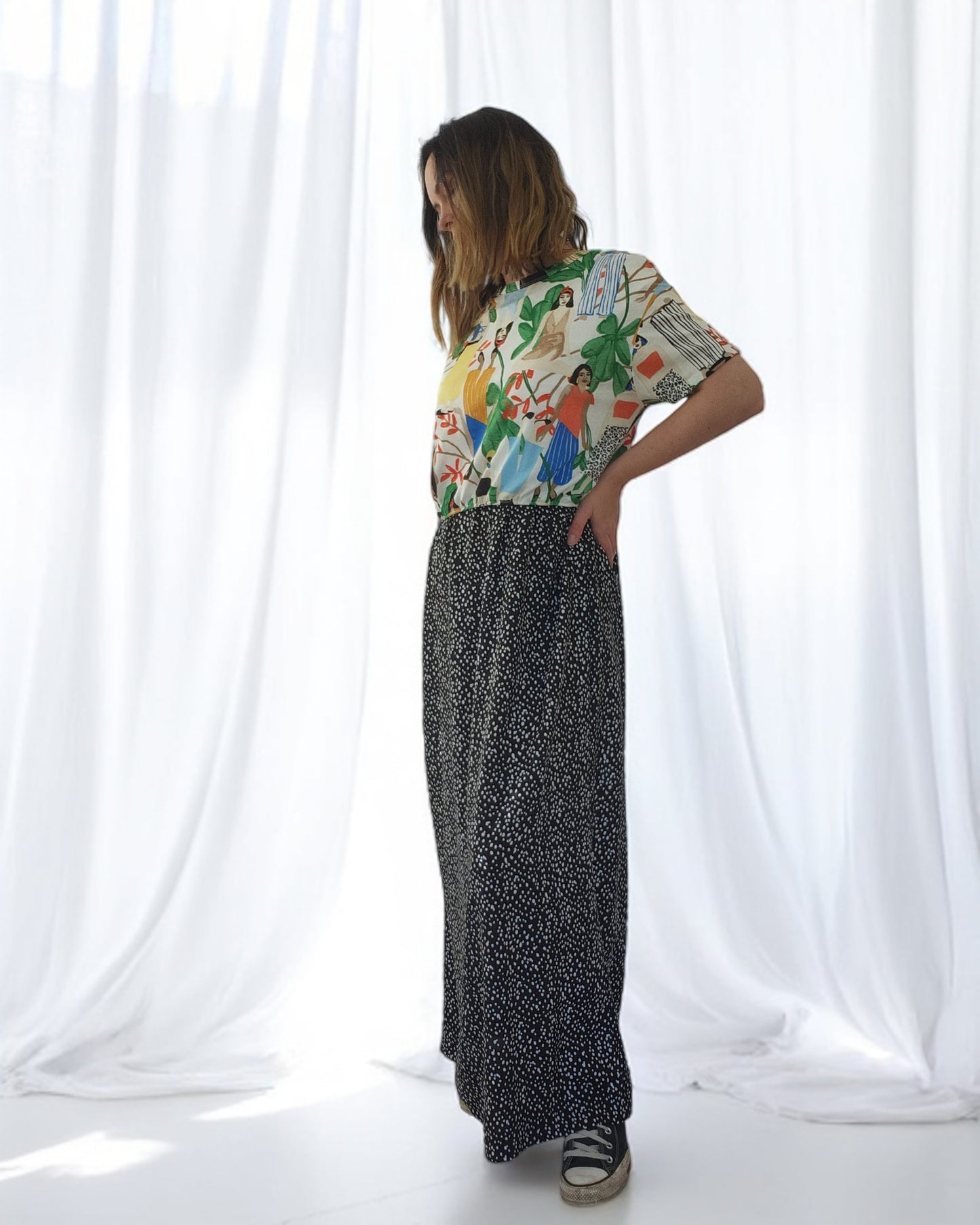 In a well-lit room with white curtains, a person confidently dons the Upcycled Breastfeeding & Pumping ZARA Tropical Maxi Dress by touched out mama. They strike a pose, embodying eco-friendly fashion while wearing chic black platform sandals.