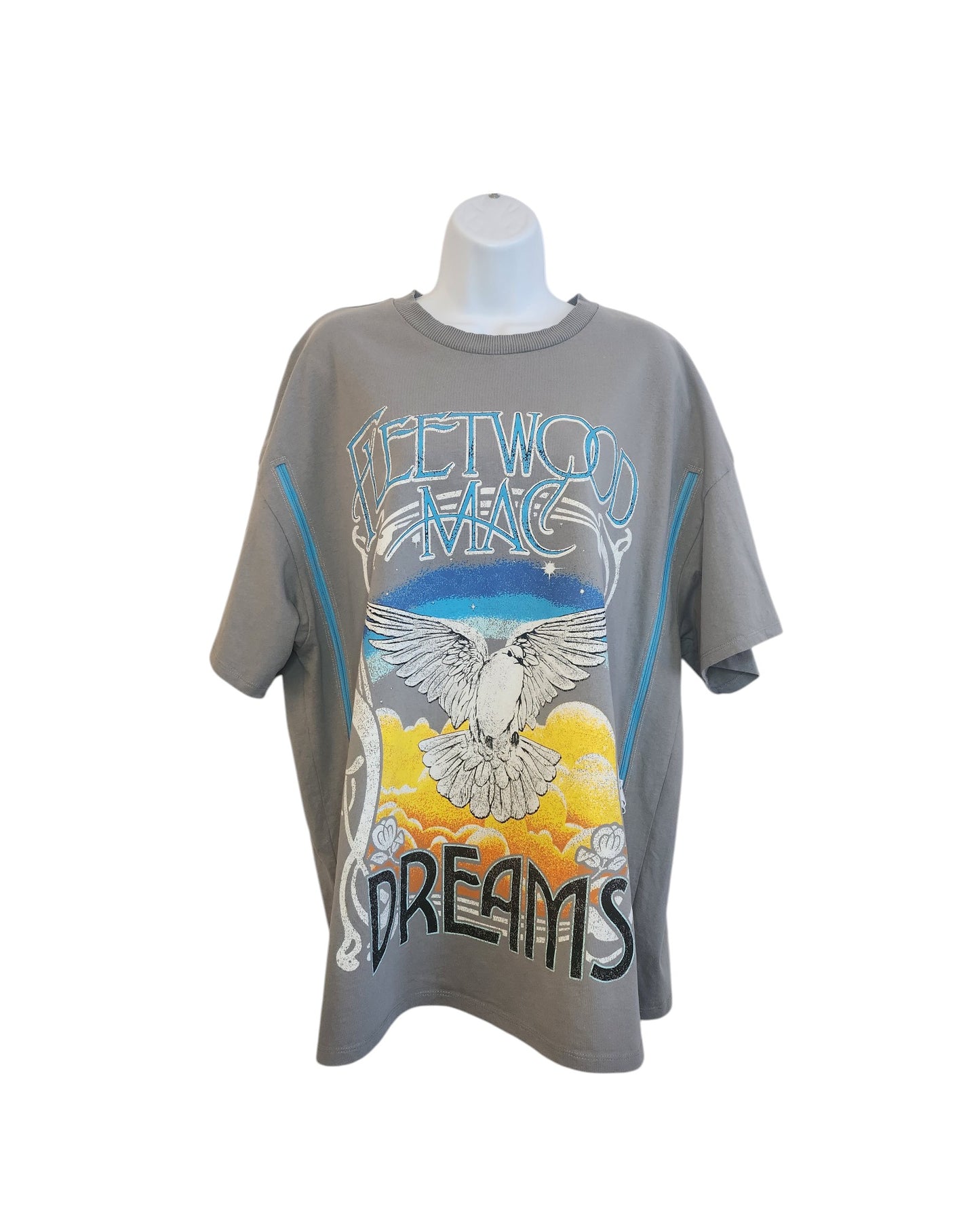 The touched out mama Upcycled Breastfeeding & Pumping Dreams Fleetwood Mac T-shirt in large showcases a vibrant design with Fleetwood Mac text, a white dove flying over sunset clouds, and Dreams at the bottom. Crafted from upcycled clothing, its displayed on a white mannequin torso.
