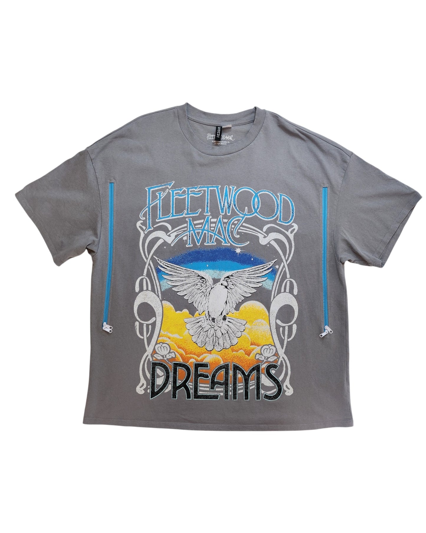 The Upcycled Breastfeeding & Pumping Dreams Fleetwood Mac t-shirt by touched out mama features decorative lettering, a white bird illustration soaring over orange clouds and blue sky, framed by artistic swirls, making it a standout piece in eco-friendly fashion.