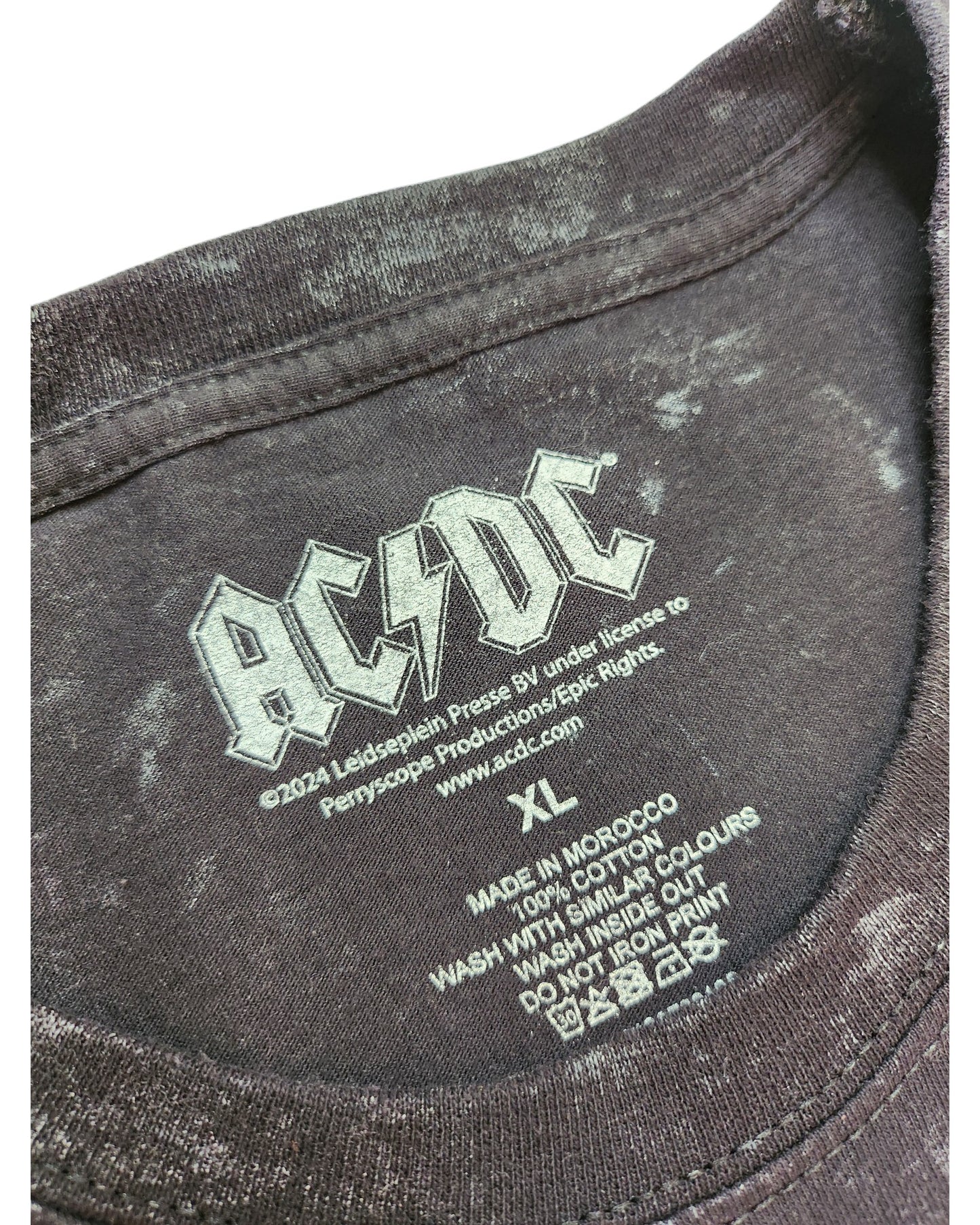 Close-up of a black t-shirt neck label featuring the iconic AC/DC band logo from touched out mama. This eco-friendly XL floral nursing & pumping tee is made in Morocco, 100% cotton from upcycled clothing. Wash with similar colors, inside out, and skip ironing the print.