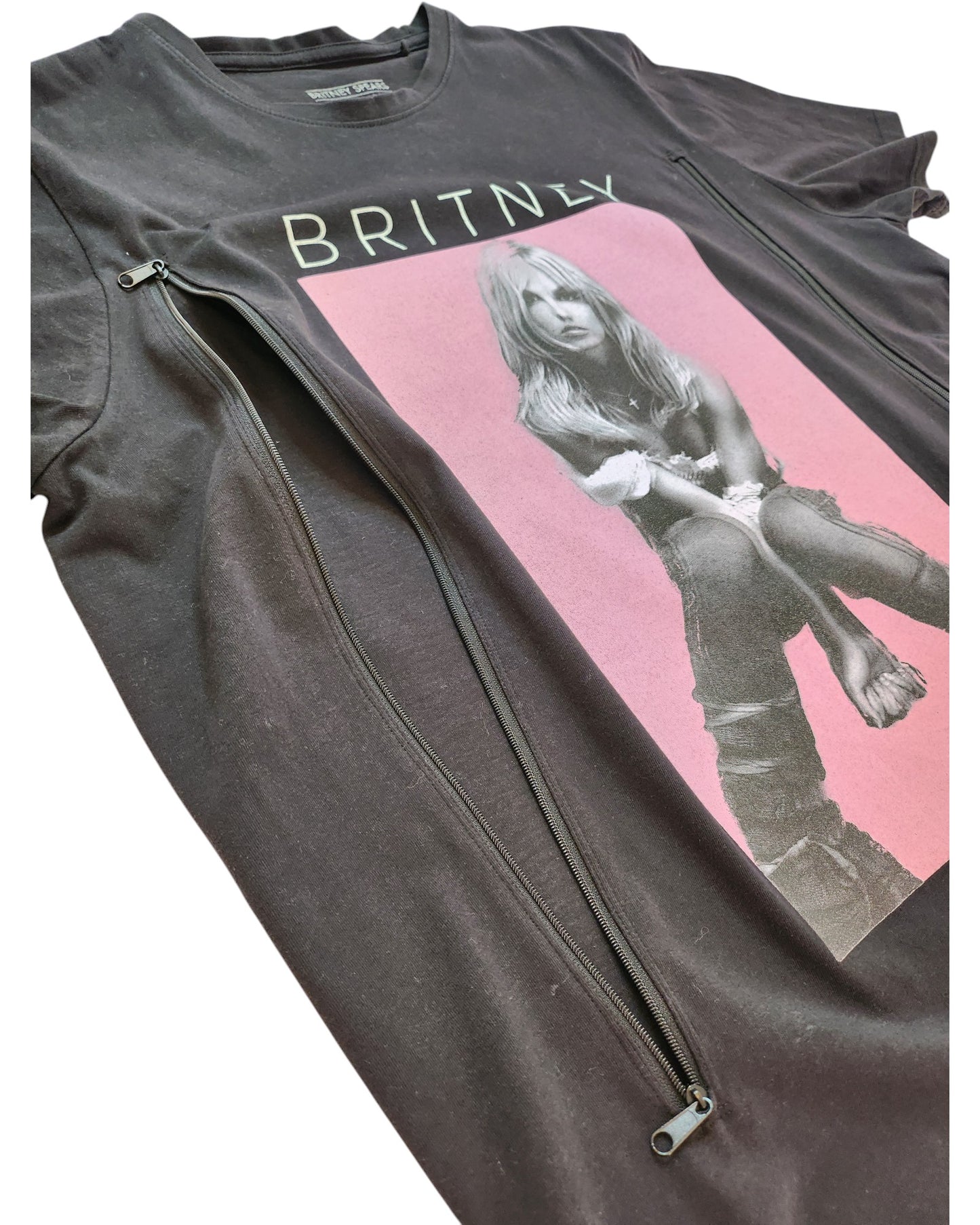 The Upcycled Breastfeeding (Nursing) & Pumping Britney t-shirt by touched out mama is a black tee with a seated photo against a pink background and BRITNEY text. Decorated with diagonal zippers, its crafted from upcycled clothing for an eco-friendly fashion.
