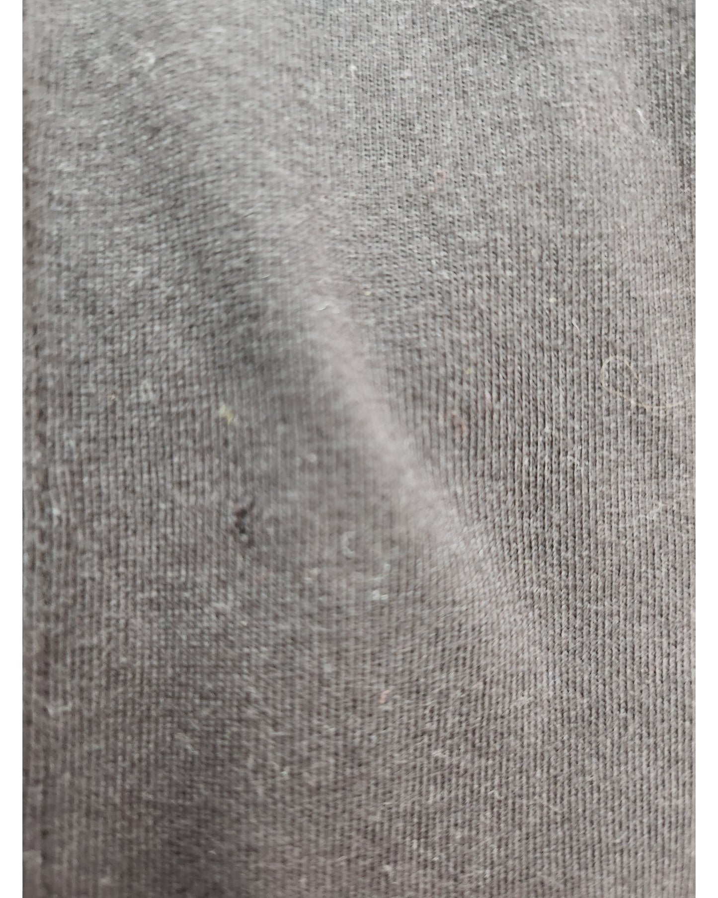 A close-up of the Upcycled Breastfeeding & Pumping Britney t-shirt by touched out mama showcases its gray fabric with a soft texture, reminiscent of upcycled clothing. Visible weave, tiny speckles, and slight folds add depth and movement to this sustainable textile.