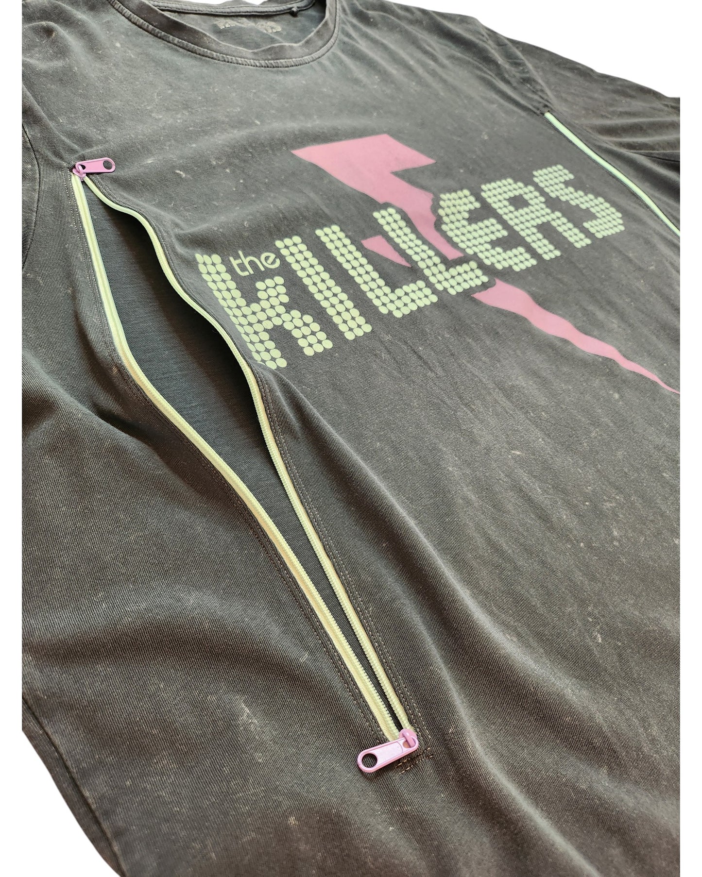 A preloved touched out mama 2XL black T-shirt features The Killers logo in white dots, a pink lightning bolt, and two open diagonal zippers with pink tags on the front for an upcycled flair. Fabric shows slight wear—ideal as a unique nursing and pumping top.