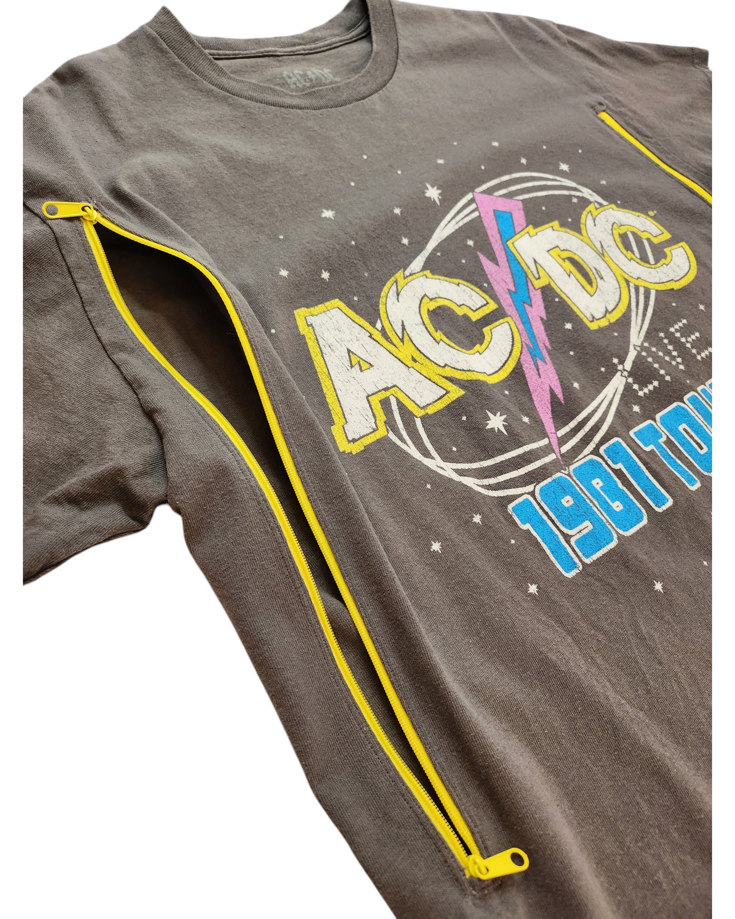 The touched out mama Upcycled Breastfeeding & Pumping Grey AC/DC Tour t-shirt features a retro 1981 graphic adorned with stars and a yellow lightning bolt. It has bright yellow zippers on the sides for a unique twist. Suitable for nursing and pumping, this piece is available in XL.