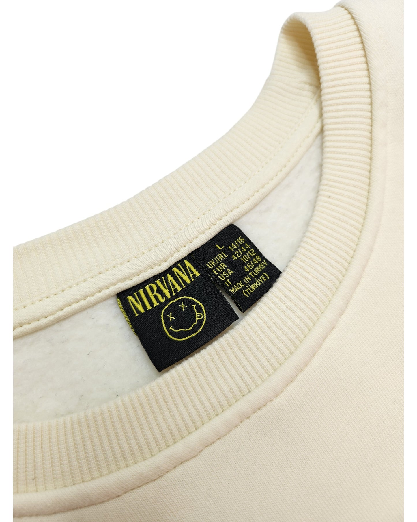 The cream-colored Nirvana sweatshirt from touched out mama, featuring a smiley logo and sizing info on the label, showcases plush fabric. This sustainable choice embodies affordable eco-friendly fashion for style-conscious consumers who value environmental responsibility (Size: L).