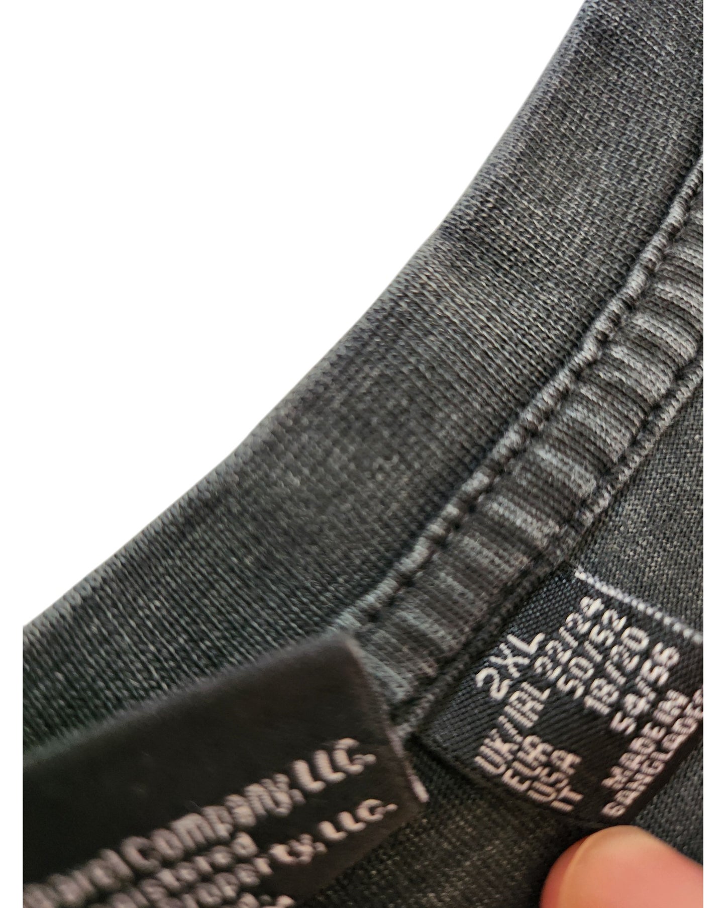 Close-up of the inside neckline of a dark Upcycled Breastfeeding & Pumping The Doors t-shirt Dress 2XL by Primark, showing tags with size and care instructions, held by a persons fingers. Eco-friendly design.