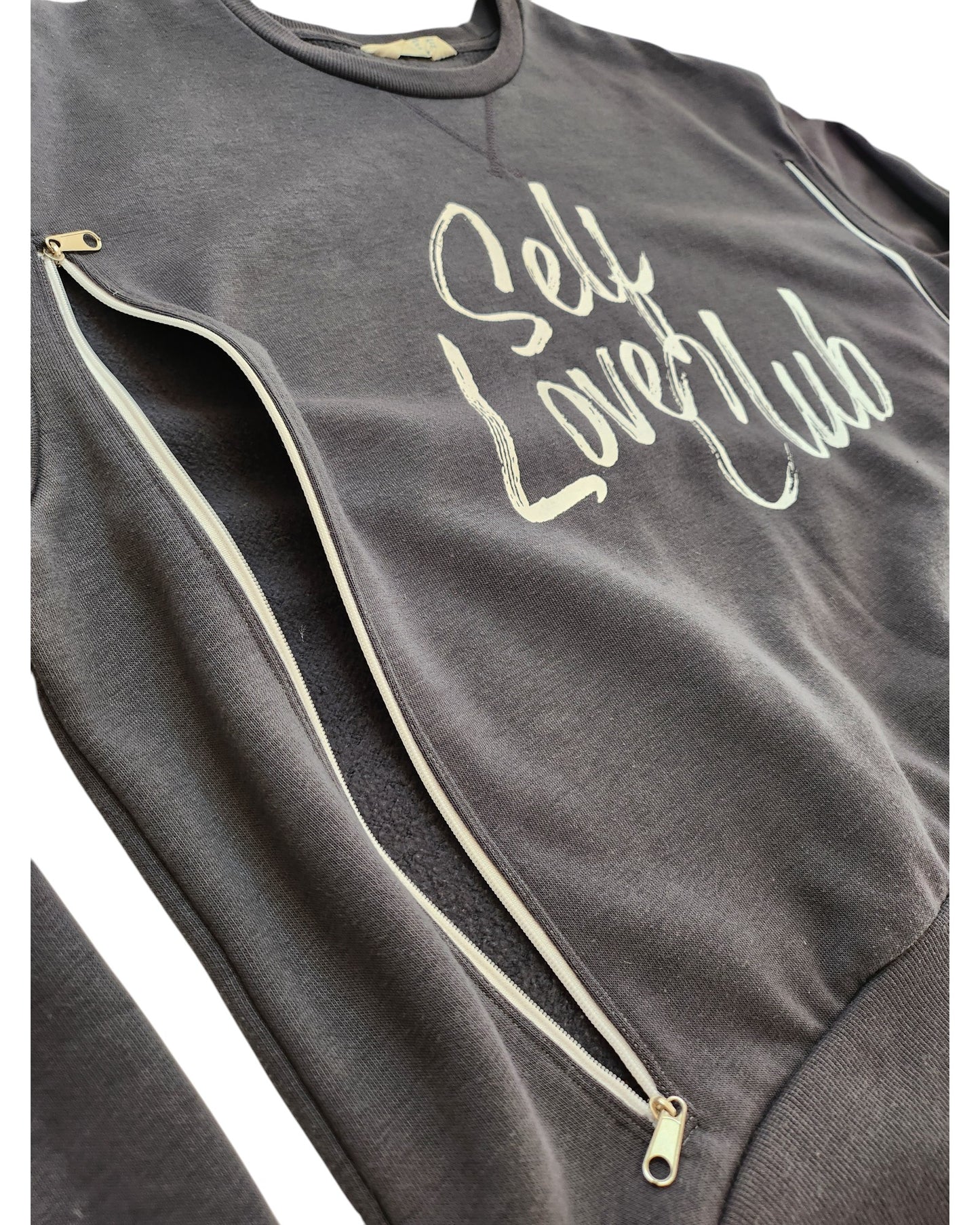 Close-up of the Primark Upcycled Breastfeeding & Pumping Grey Self Love Club Sweatshirt (L, UK14/16) with white side zippers and Self Love Club in white cursive on the front.