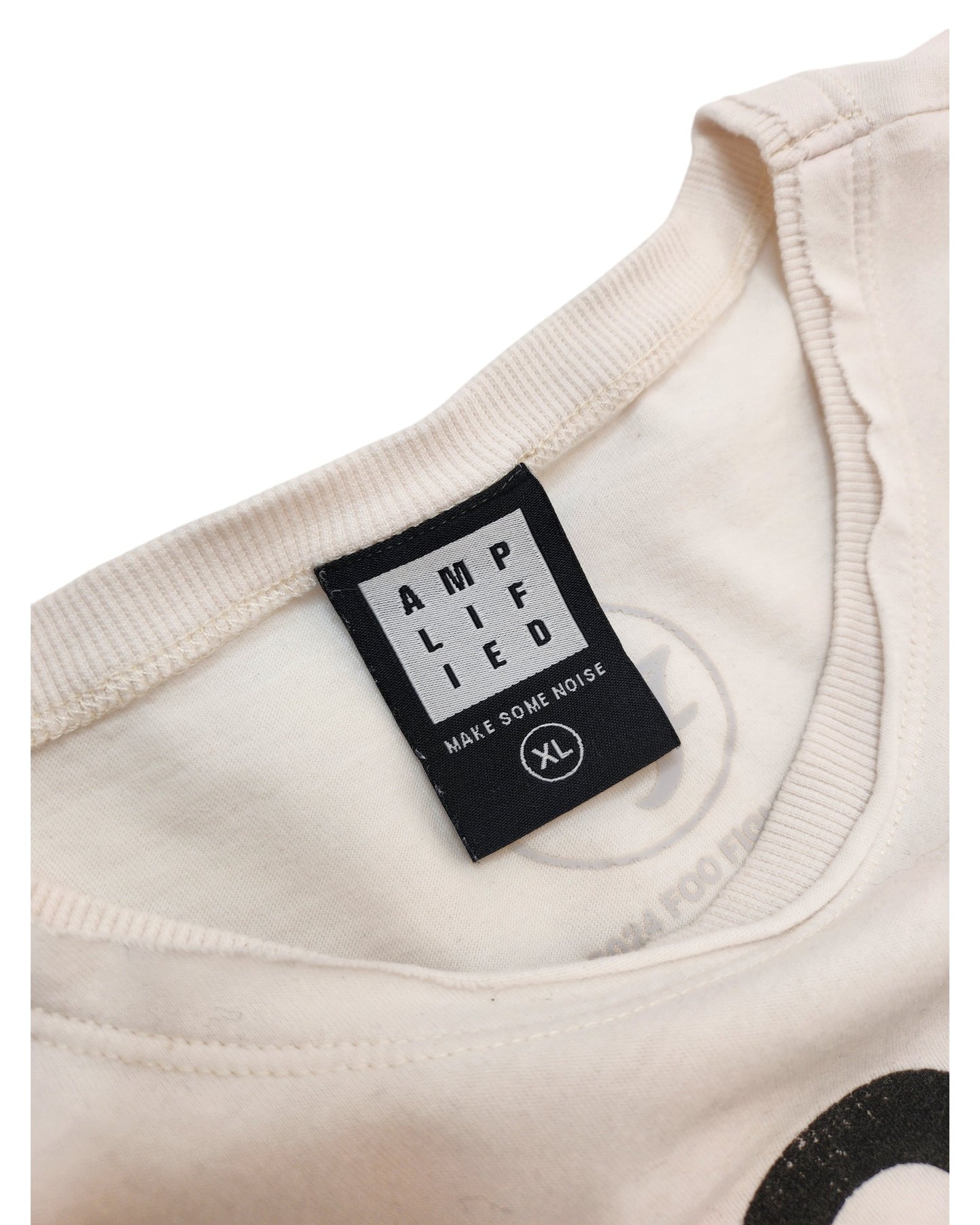 Close-up of the collar on this cream-colored, upcycled XL Amplified Breastfeeding & Pumping Foo Fighters t-shirt, featuring a black label with white text and a faint circular preloved logo inside—showcasing unique fashion details.