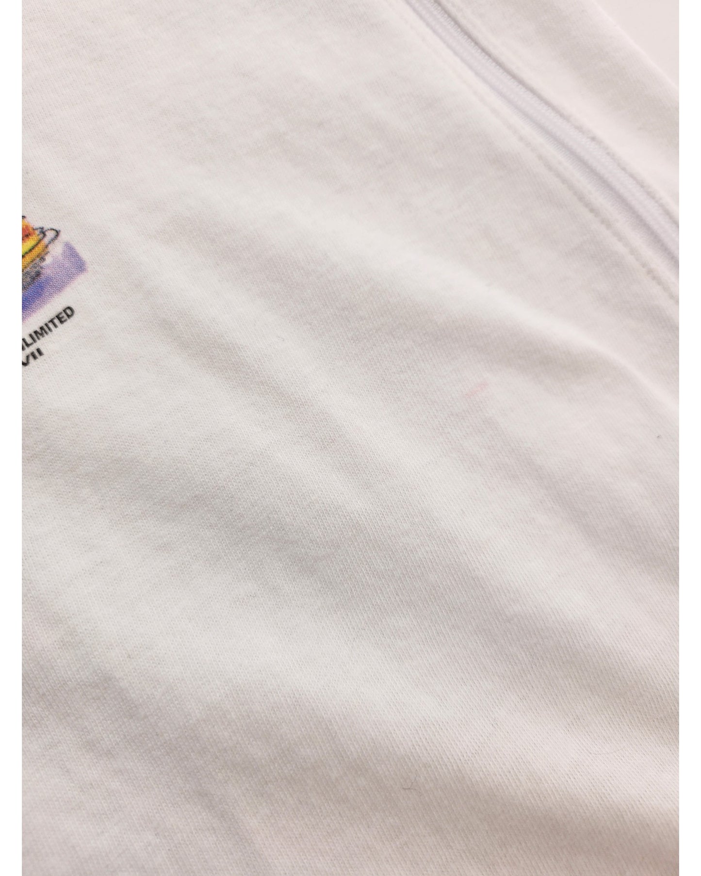 Close-up of Sun Wear’s Upcycled Breastfeeding & Pumping Times Square t-shirt (L) in white, featuring a soft, slightly textured fabric with a small colorful print at the upper left and a partially visible zipper on the right.