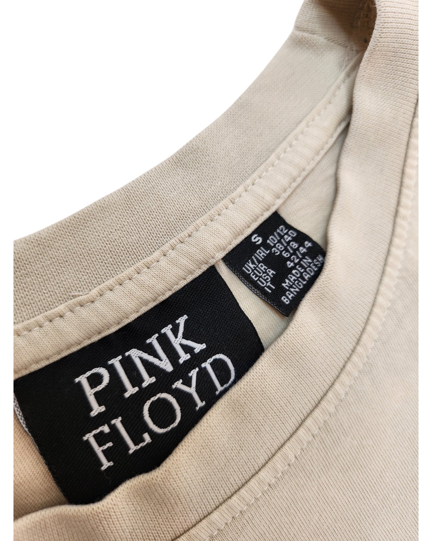 Close-up of an upcycled Primark breastfeeding & pumping Pink Floyd t-shirt (cream, size S UK10/12) neckline, showing two labels: a prominent black PINK FLOYD tag and a smaller label with size and care instructions.