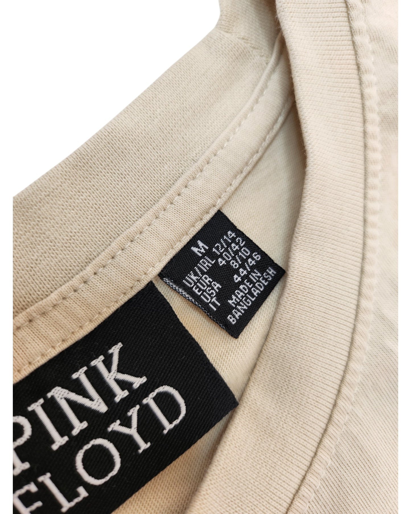 Close-up of an Upcycled Cream Pink Floyd Band t-shirt (M/UK12/14) by Primark, showing the label and UK, EU, USA size tags. This preloved breastfeeding & pumping top was made in Bangladesh.