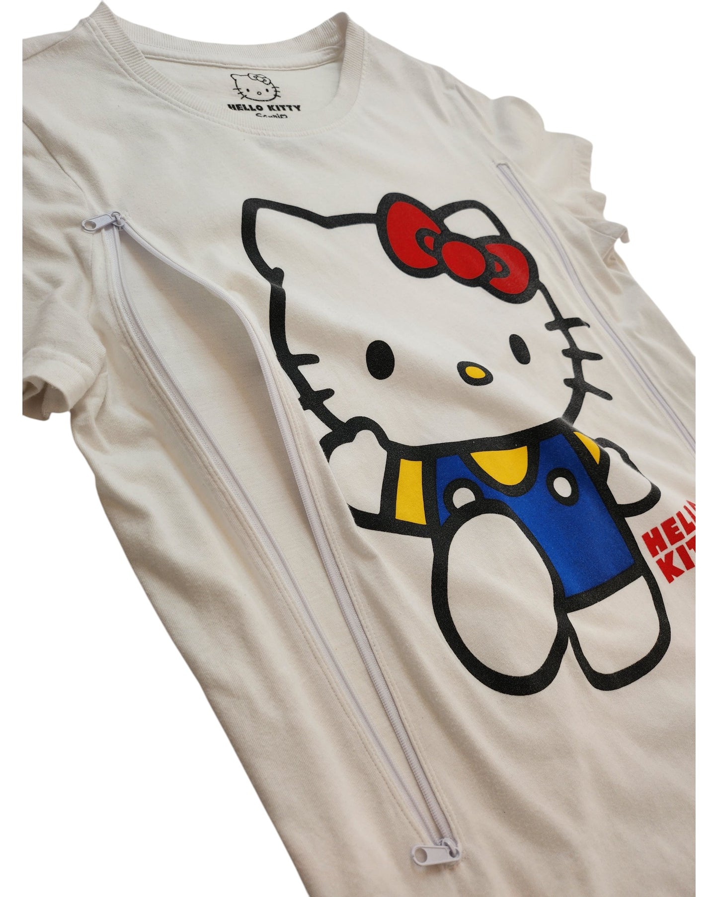 Primark Upcycled Breastfeeding & Pumping White Hello Kitty T-shirt (S, UK10/12) features a bold graphic with blue/yellow overalls and two side zippers—ideal preloved clothing for comfortable nursing and pumping.