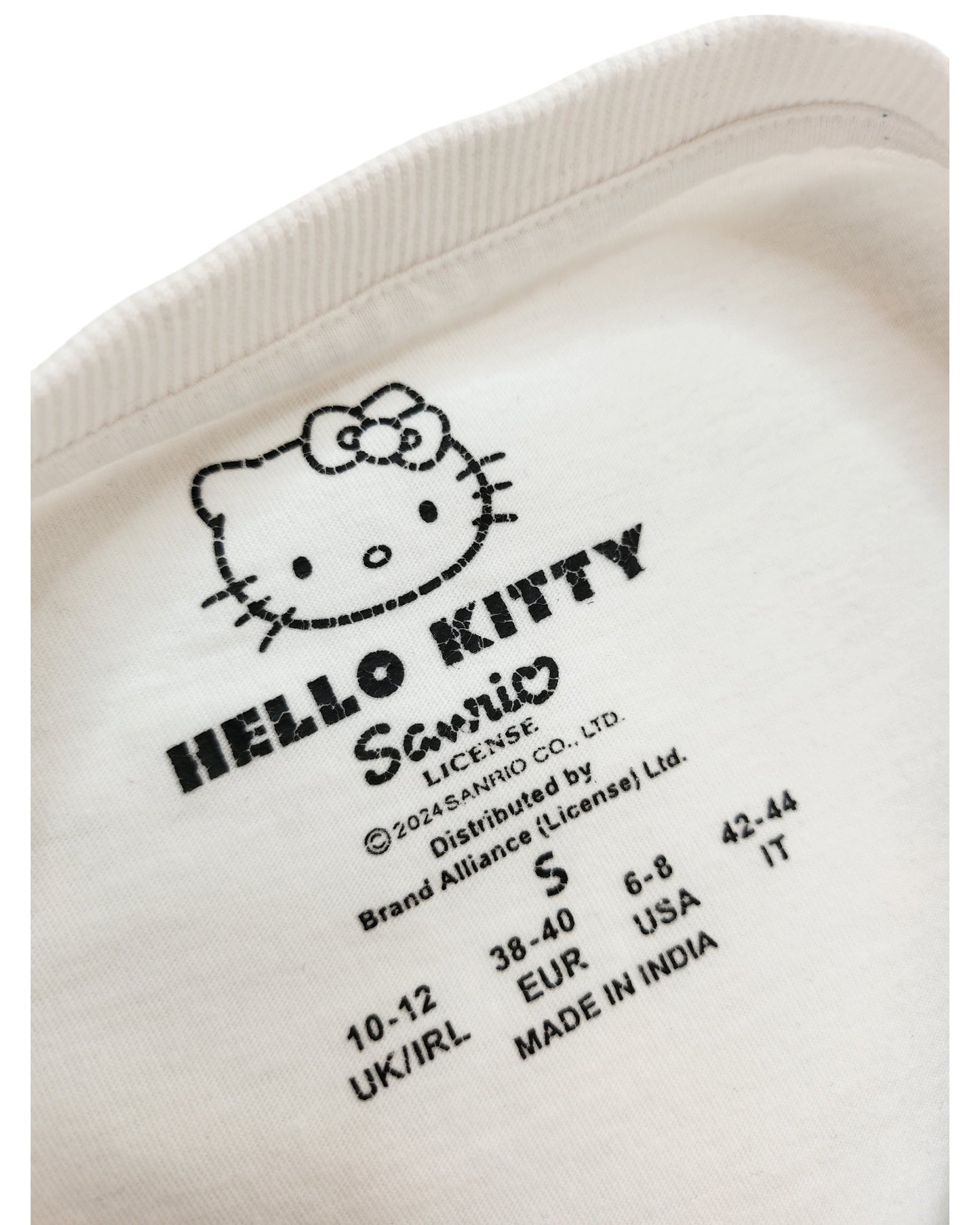 Close-up of a white Primark clothing label on an Upcycled Breastfeeding & Pumping Hello Kitty t-shirt (S/UK10/12), showing the character, logo, regional sizing, and Made in India—ideal for fans of upcycled apparel.