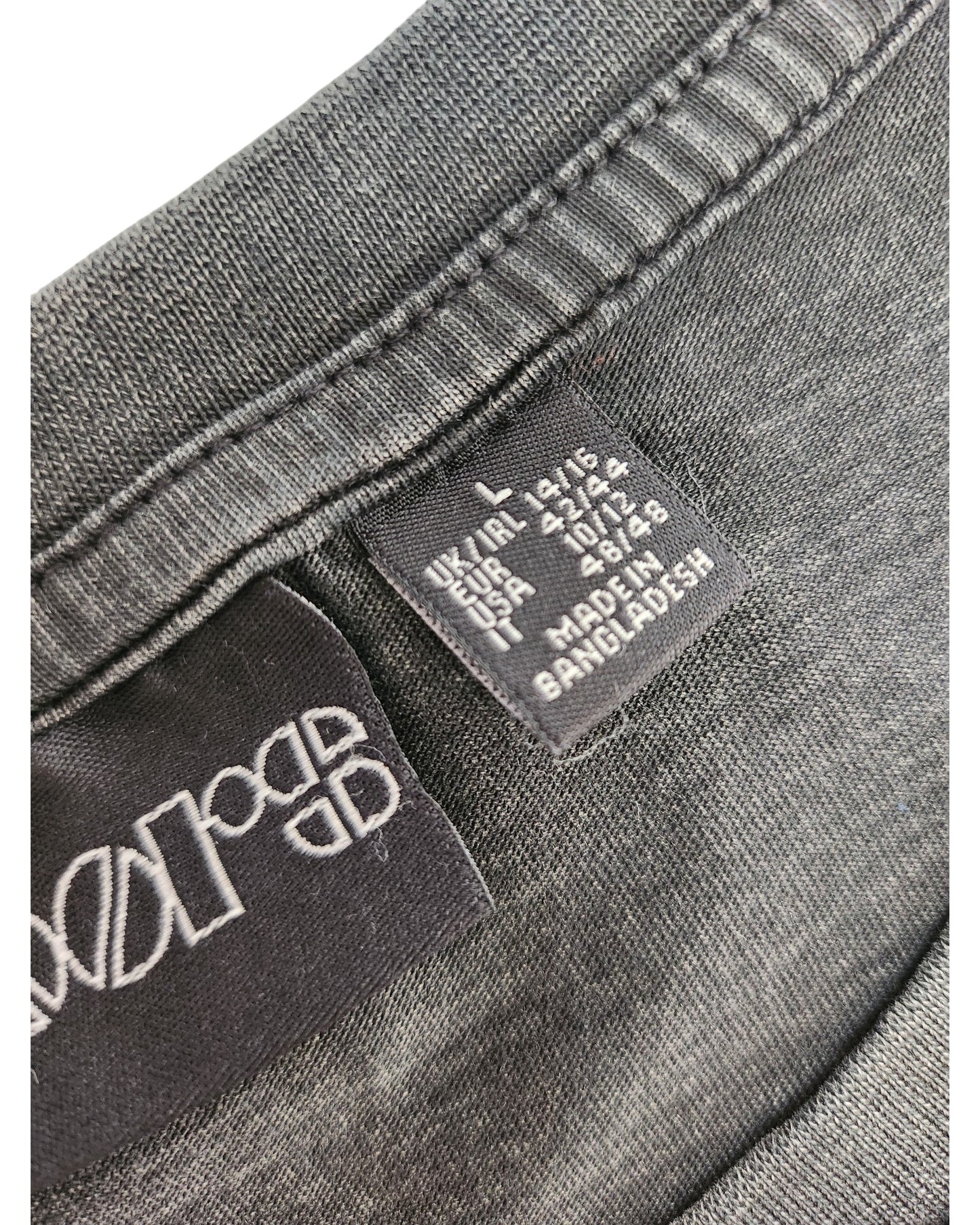 Close-up of a black Primark tag inside the Upcycled Breastfeeding & Pumping The Doors Band t-shirt dress (L/UK14/16) made from dark grey fabric, showing UK, EU, USA sizes and MADE IN BANGLADESH—great for quality preloved clothing seekers.