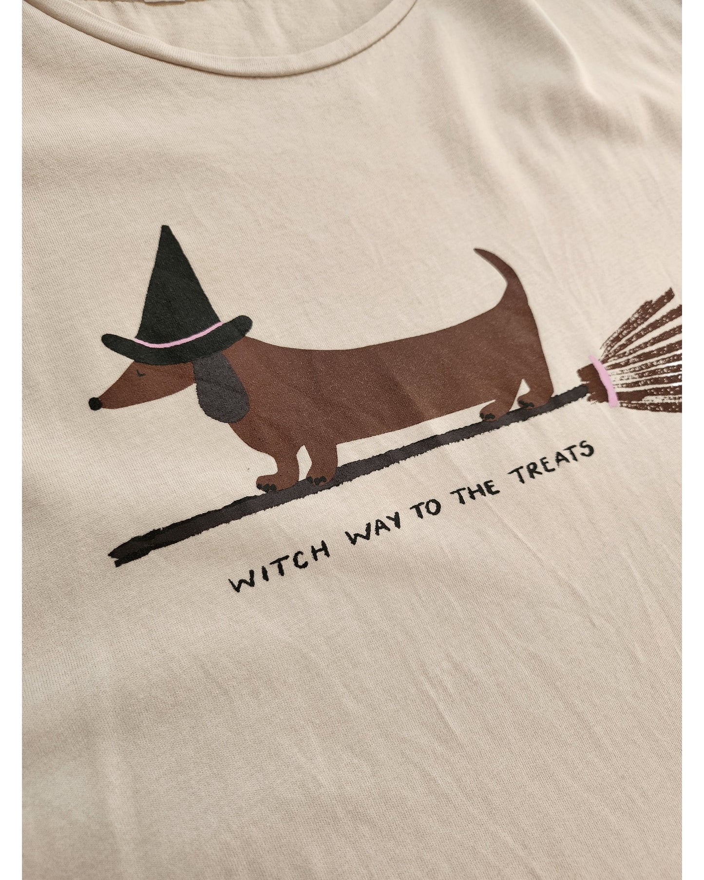 The Tu Upcycled Breastfeeding & Pumping Witch Dog t-shirt Nightdress L features a dachshund in a witch hat on a broom, with WITCH WAY TO THE TREATS text. Made from soft upcycled fabric for an eco-friendly Halloween look.