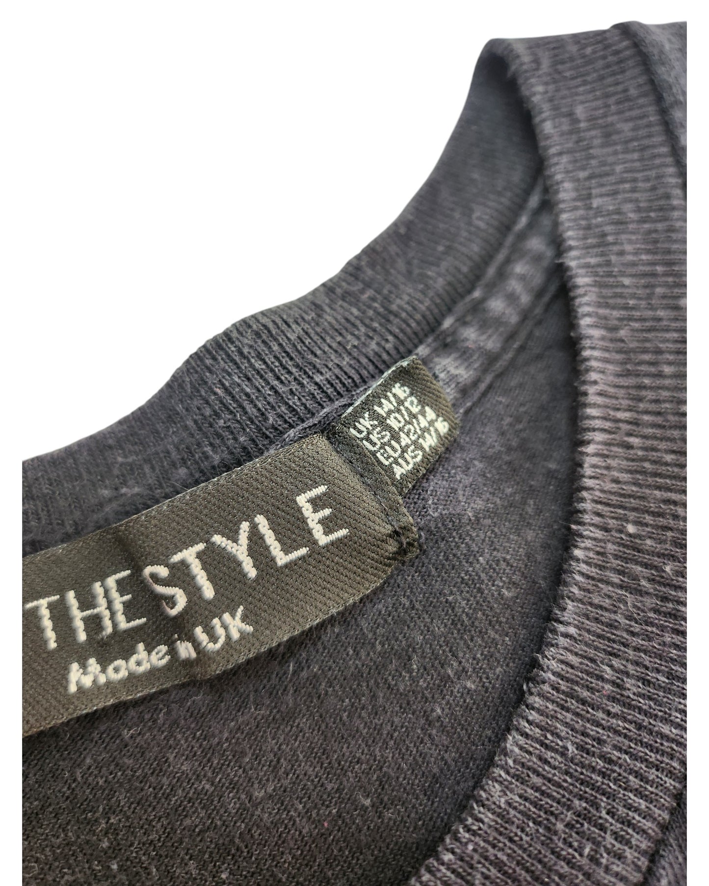 Close-up of a black clothing label on an upcycled In the Style Breastfeeding & Pumping Black/Purple Butterfly t-shirt UK14/16, showing size info for UK, EU, US. An eco-friendly wardrobe choice.