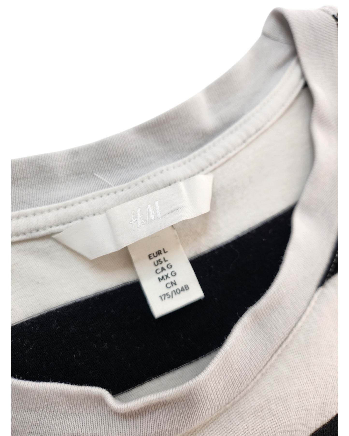 Close-up of an H&M label inside an Upcycled Breastfeeding & Pumping Black/White Stripe t-shirt (L), showing size info for regions: EUR L, US L, CA G, MX G, and 175/104B.