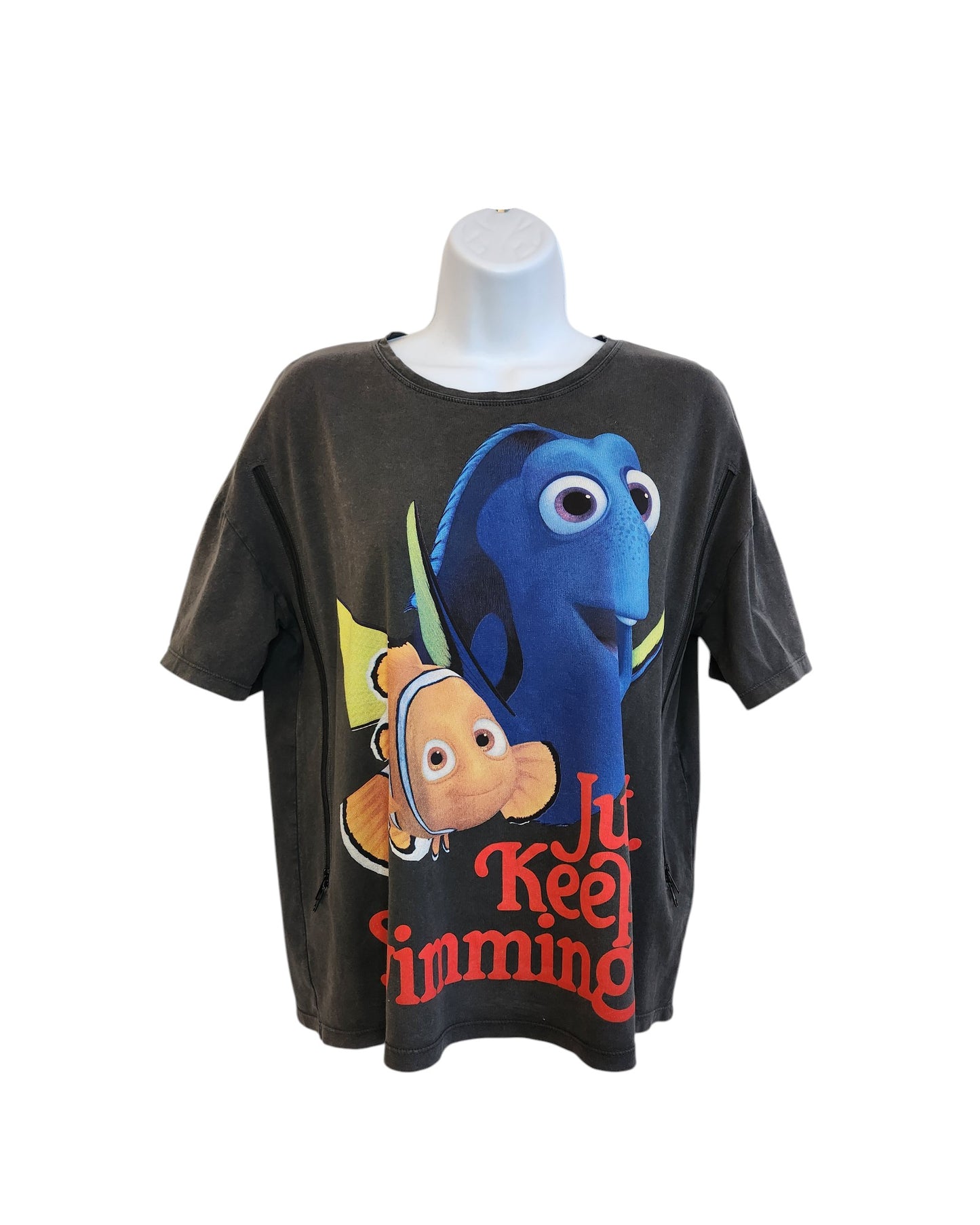 A preloved ZARA Upcycled Breastfeeding & Pumping Nemo T-shirt (size M), featuring large images of Dory and Nemo with Just Keep Swimming in bold red, is displayed on a white mannequin torso.
