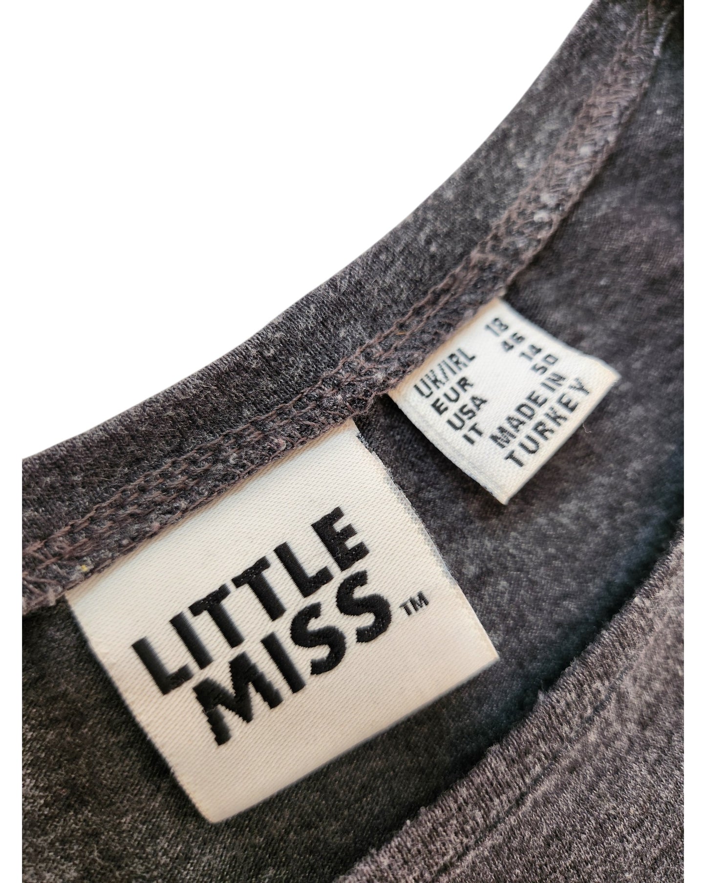 Close-up of a gray Primark t-shirts neckline with two labels: one reads LITTLE MISS™, the other lists size (UK 18) and MADE IN TURKEY—ideal for fans of upcycled breastfeeding & pumping fashion.