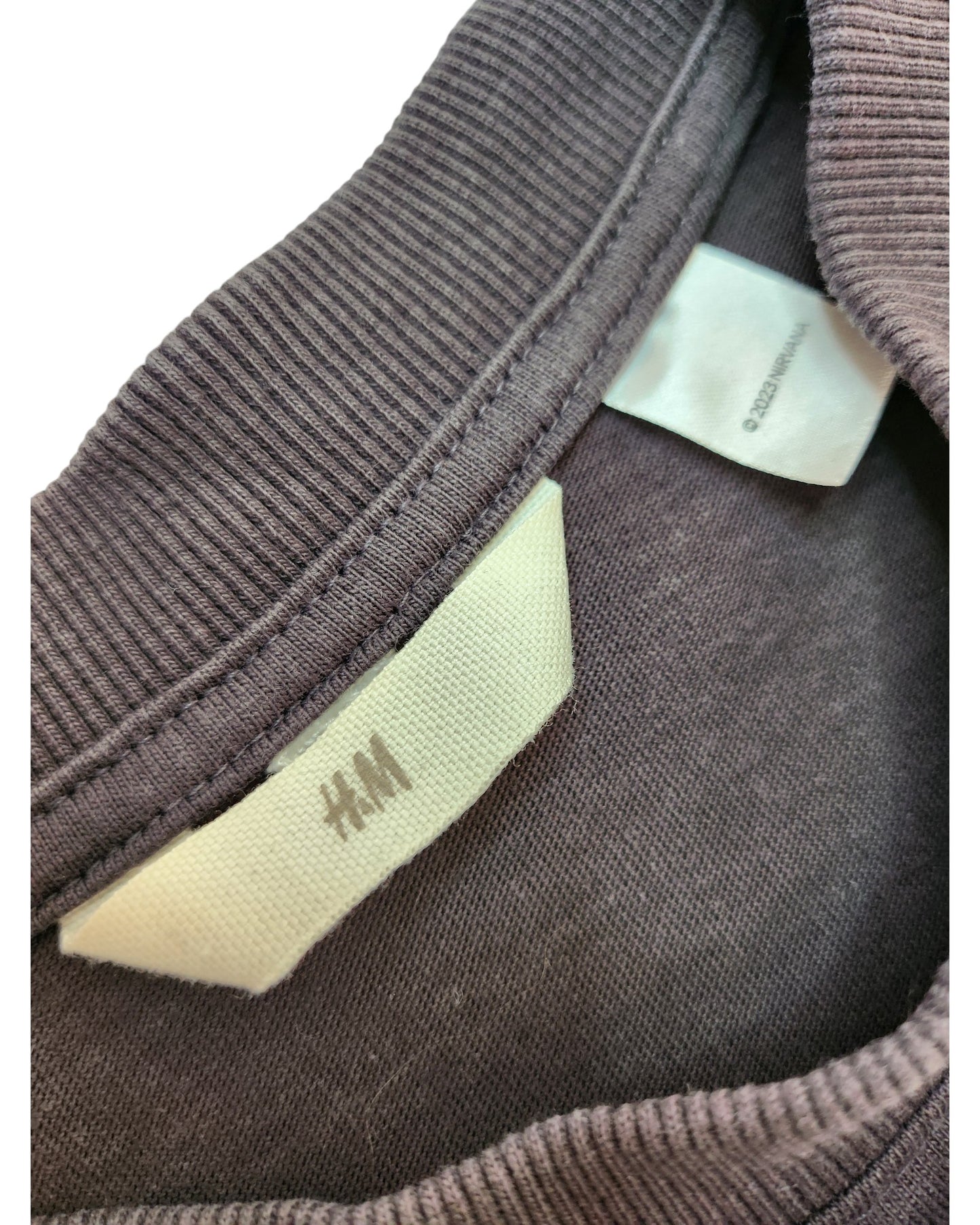 Close-up of the gray ribbed crewneck on the Upcycled Breastfeeding & Pumping Dark Grey/Cream Nirvana Angel t-shirt (L) by H&M, featuring a white brand tag and care label inside the neckline.