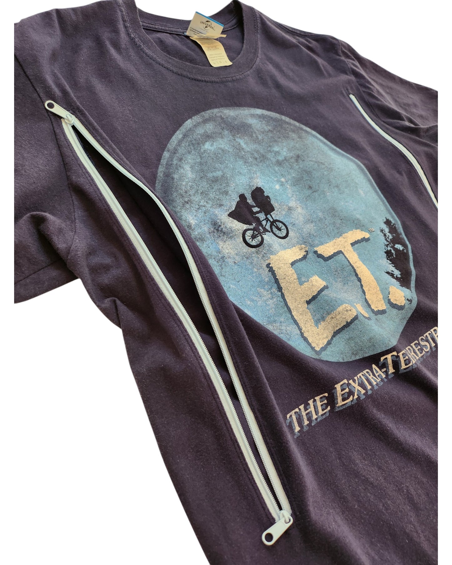 The Gildan Upcycled Breastfeeding (Nursing) & Pumping ET t-shirt L features the iconic E.T. graphic and discreet diagonal zippers, offering stylish and practical access for nursing or pumping moms.