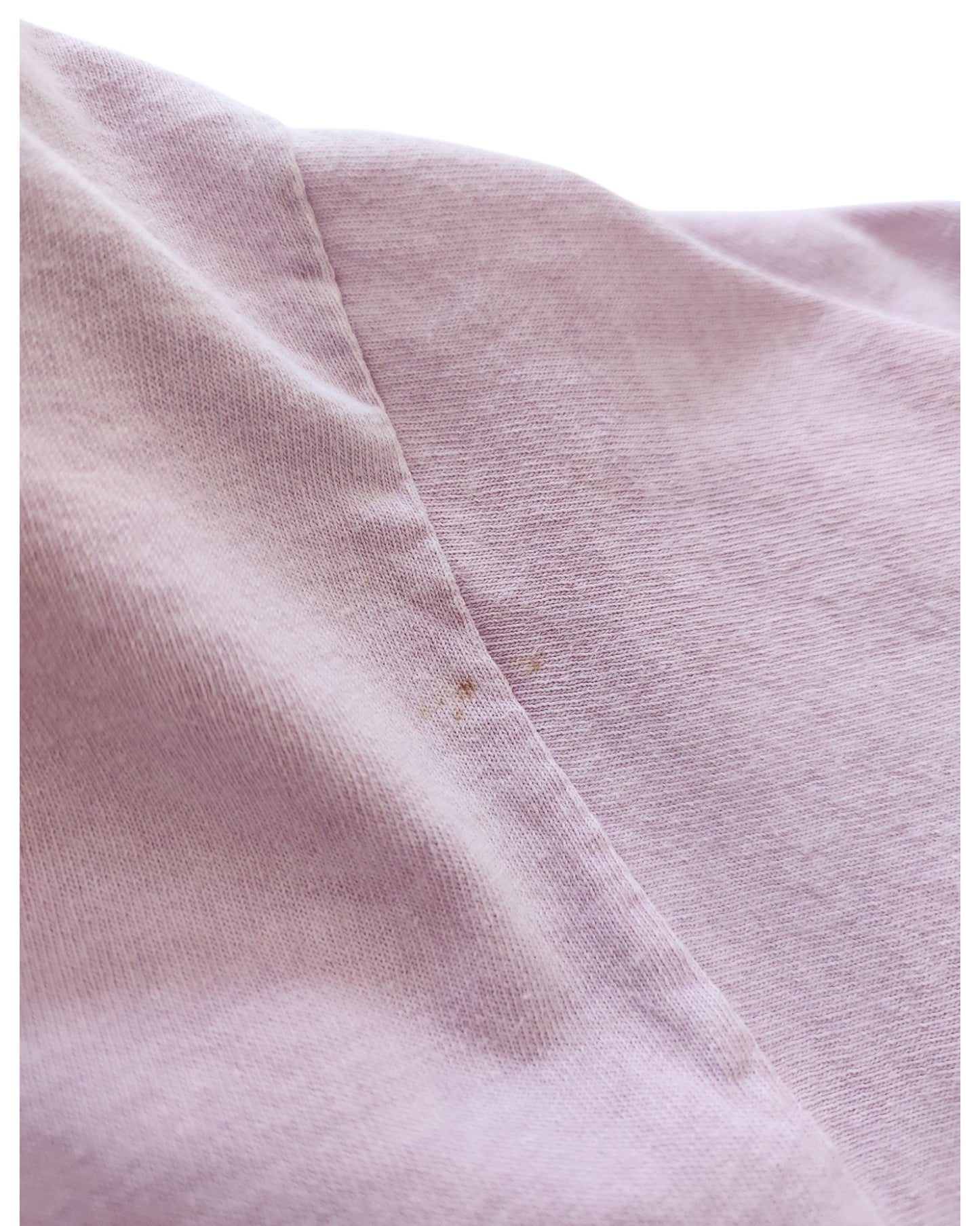 A close-up of the Upcycled Breastfeeding & Pumping Lilac AC/DC t-shirt (M) shows a vertical seam with a faint brownish stain by the stitching—great for fans of preloved AC/DC fashion.