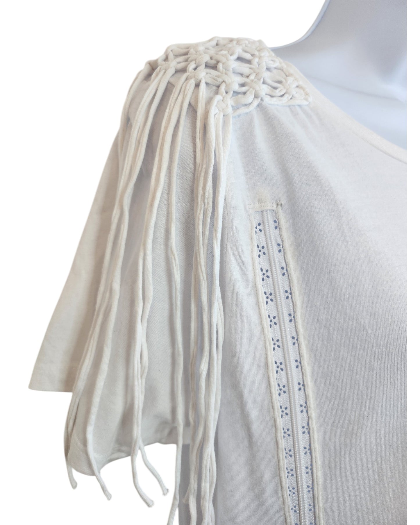 A close-up of the Pep & Co Upcycled Breastfeeding & Pumping Plain White Shoulder Fringing t-shirt UK12, featuring eco-friendly braided macramé fringing with long tassels and decorative eyelet trim on the front.