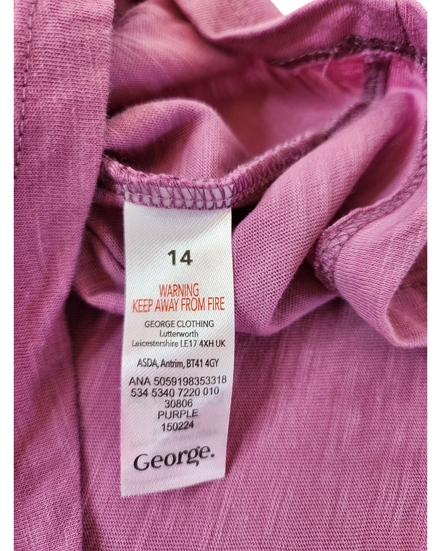 Close-up of a clothing label on a purple George Upcycled Breastfeeding (Nursing) & Pumping Sprite t-shirt, UK14. The preloved label shows size 14, fire safety warning, care instructions, and manufacturer details.