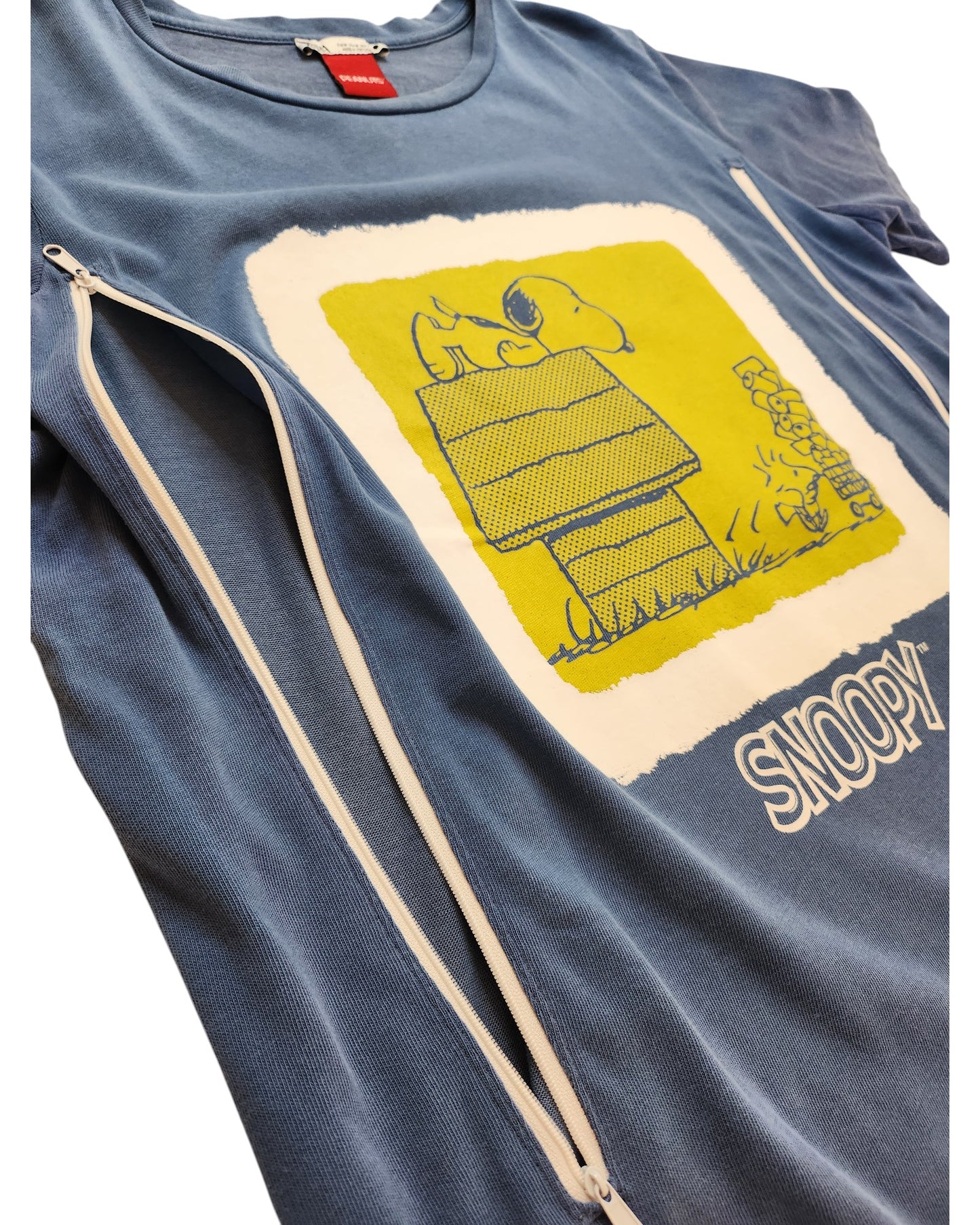 The Upcycled Breastfeeding & Pumping ZARA Snoopy Blue T-shirt (M) features preloved materials, a yellow and white Snoopy on his doghouse graphic with Woodstock, and a diagonal white zipper for easy nursing access.