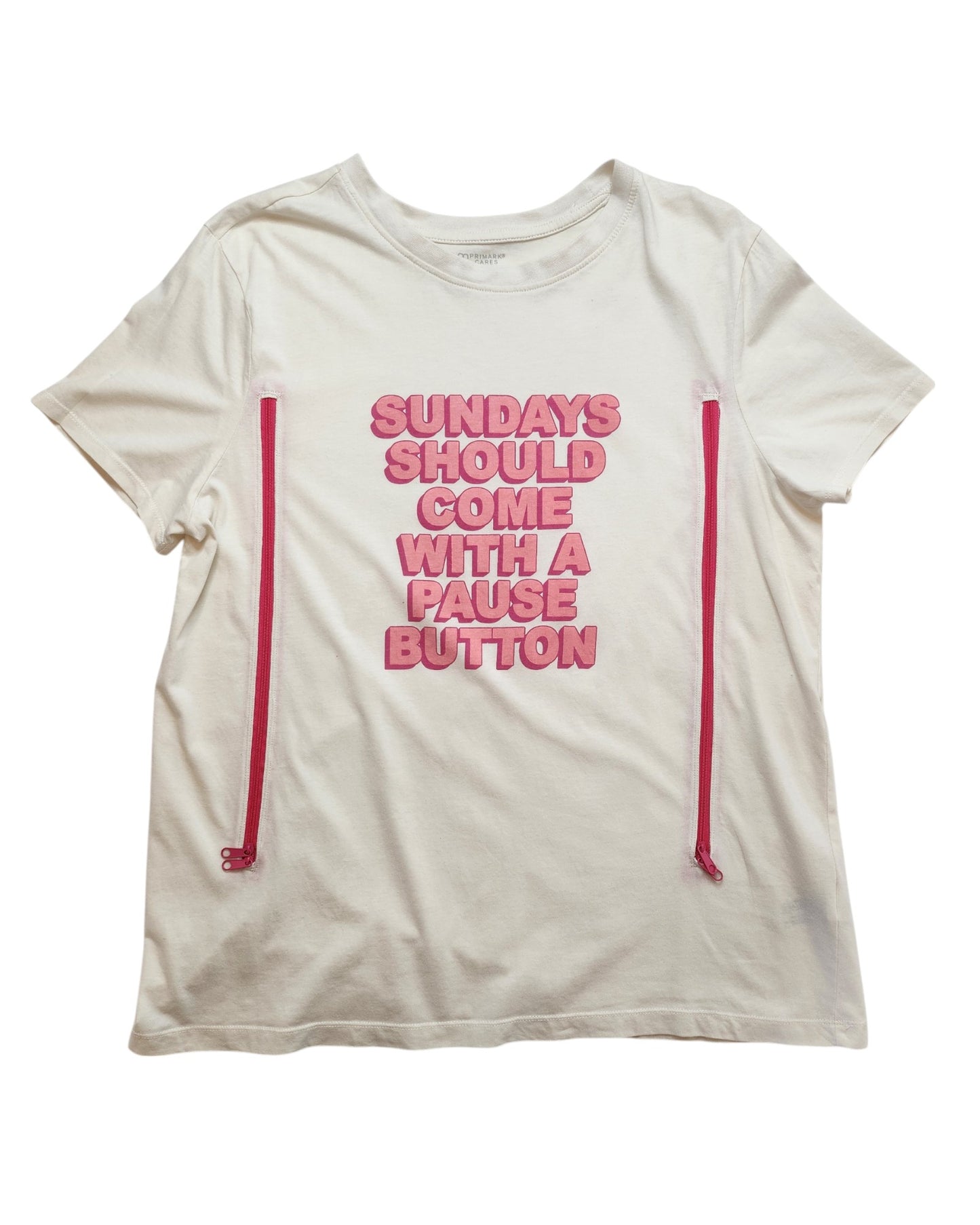 Primark’s Upcycled Breastfeeding & Pumping Sundays Pause Button t-shirt (L, UK14/16) is a white tee with pink side zippers for easy nursing and features “SUNDAYS SHOULD COME WITH A PAUSE BUTTON” in pink text on the front.