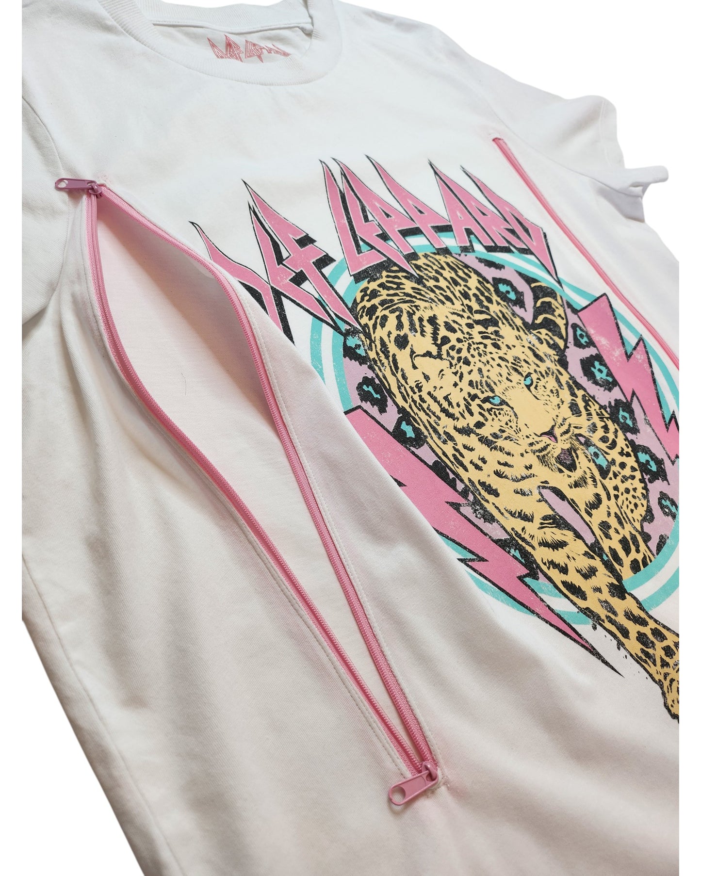 The Upcycled Breastfeeding & Pumping White/Pink Def Leppard t-shirt (L) features colorful leopard and lightning graphics, pink nursing zippers under each arm, and offers a unique style for fans of upcycled fashion.