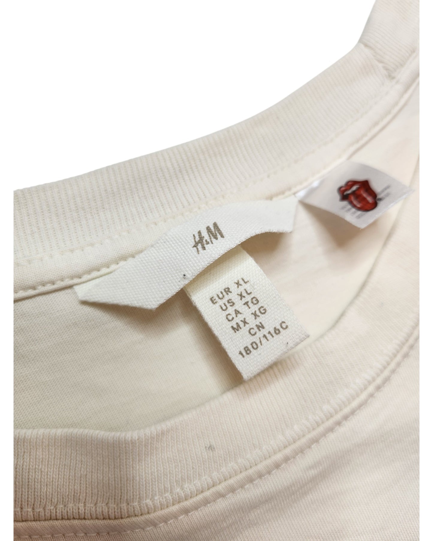 Close-up of an H&M tag inside an upcycled cream/red The Rolling Stones breastfeeding & pumping t-shirt, size XL—a stylish preloved choice for nursing moms.