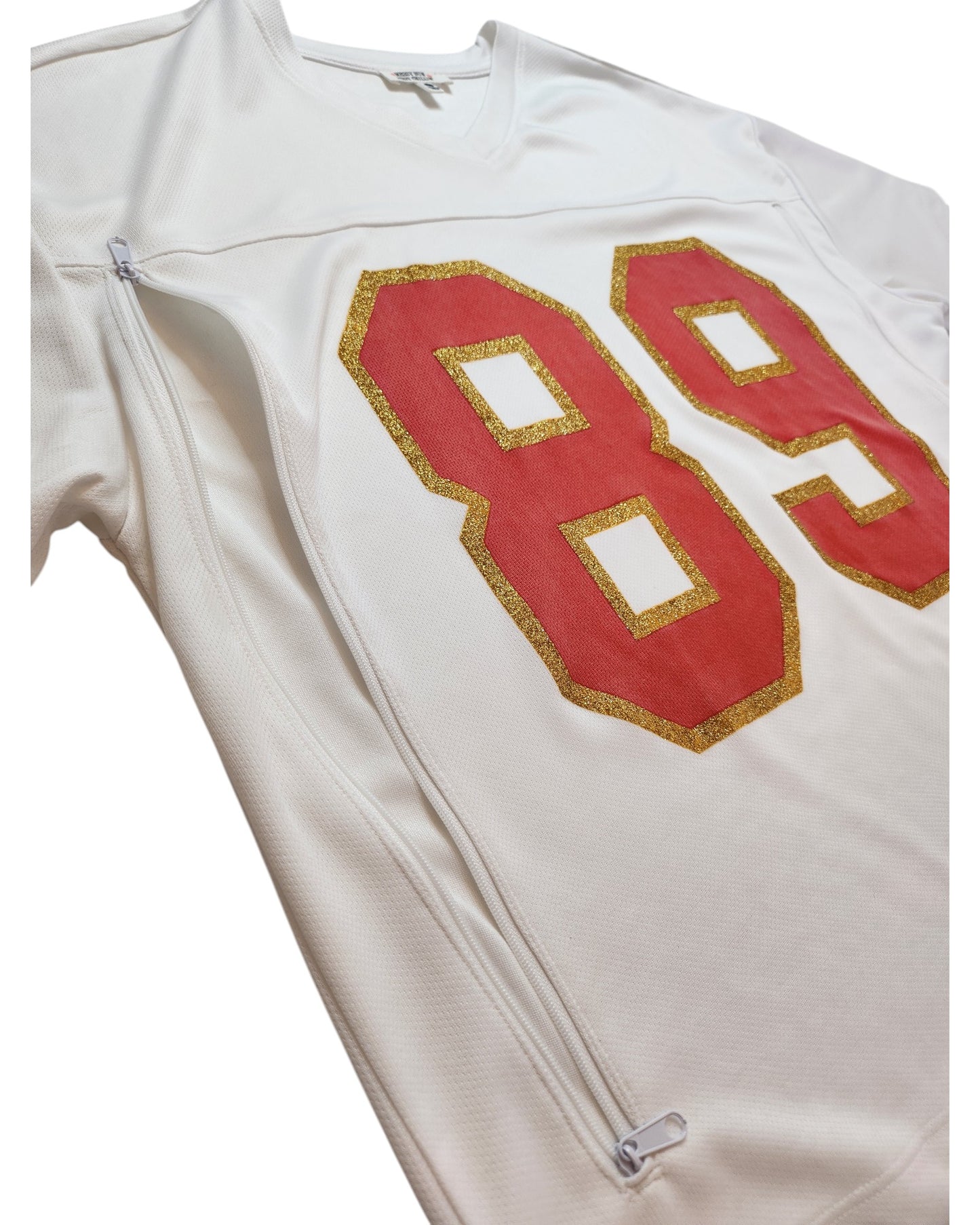 The Messy Bun Just Chillin Upcycled Breastfeeding & Pumping 89 Swiftie Football Jersey t-shirt (size L) is a white sports jersey with bold red and gold 89 on the front, featuring a visible side zipper for easy nursing and sporty style.