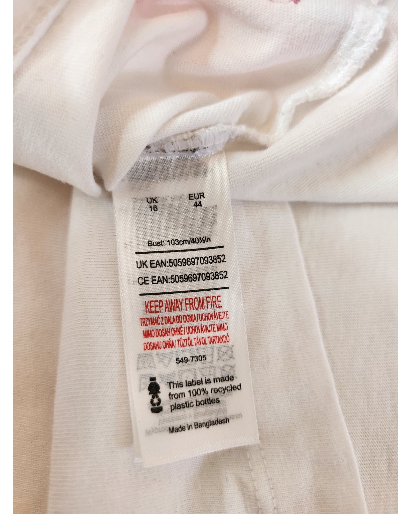 A white tag on the Upcycled Breastfeeding & Pumping White Queen t-shirt UK16 by Queen displays size, barcode, a red KEEP AWAY FROM FIRE warning, and notes the label is made from 100% recycled bottles—great for fans of upcycled clothing.